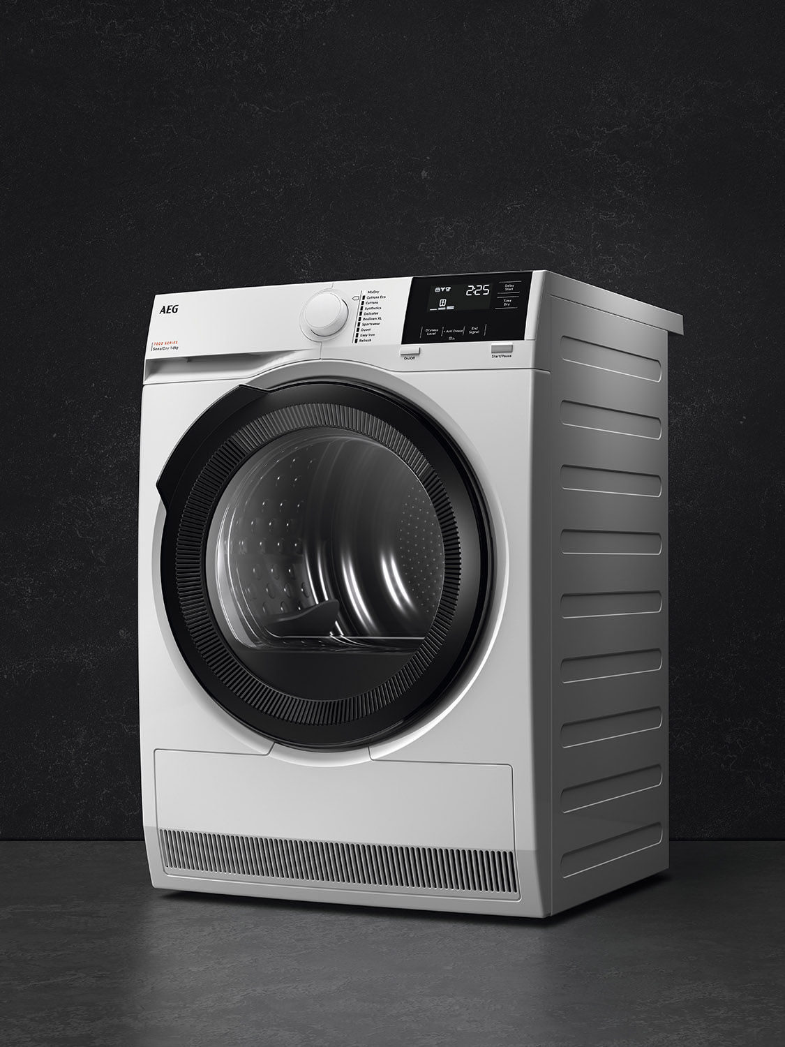 A white dryer with a dark door against a black wall, indoor setting.