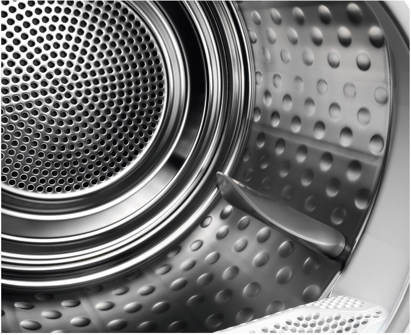 Interior of a washing machine drum with a perforated stainless steel design.