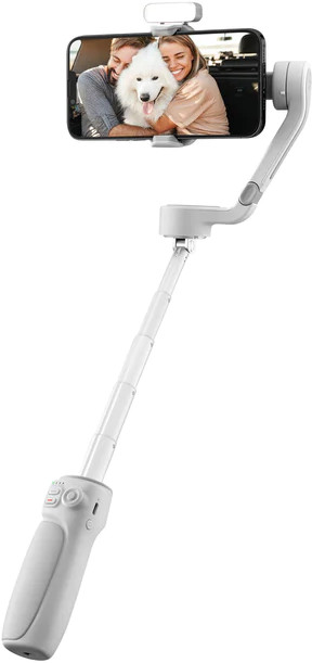 Een witte selfiestick met een telefoon waarop een stel een hond omhelst. Het heeft een bevestigde lamp en staat op een witte achtergrond.