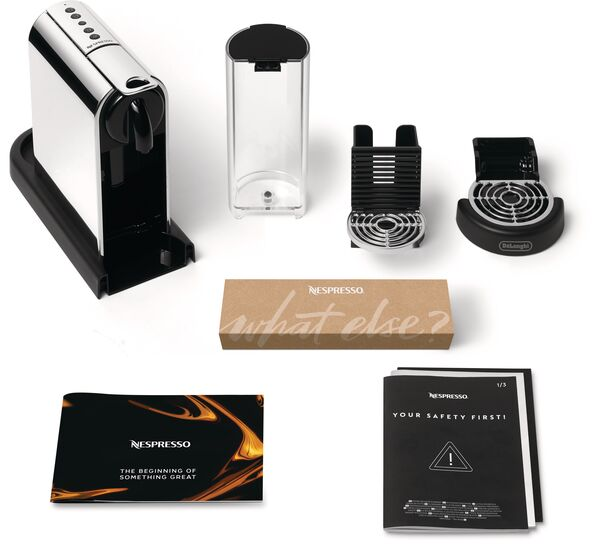 Nespresso-Kaffeemaschine und Zubehör. Enthält Maschine, Wassertank, Tropfschale, Kapselhalter und Handbücher. Verschiedene Verpackungselemente sind vorhanden.