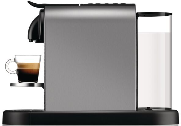 Eine silberne und schwarze Nespresso-Kaffeemaschine mit einer Tasse Kaffee daneben.