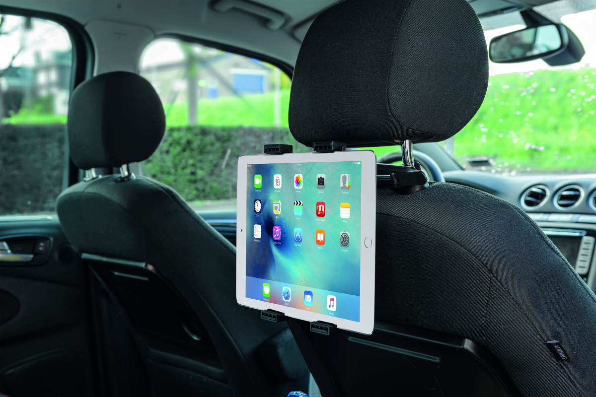 Egy iPad egy autósülés fejtámlájára van szerelve. A képernyő alkalmazásikonokat mutat. Az autó belseje látható.