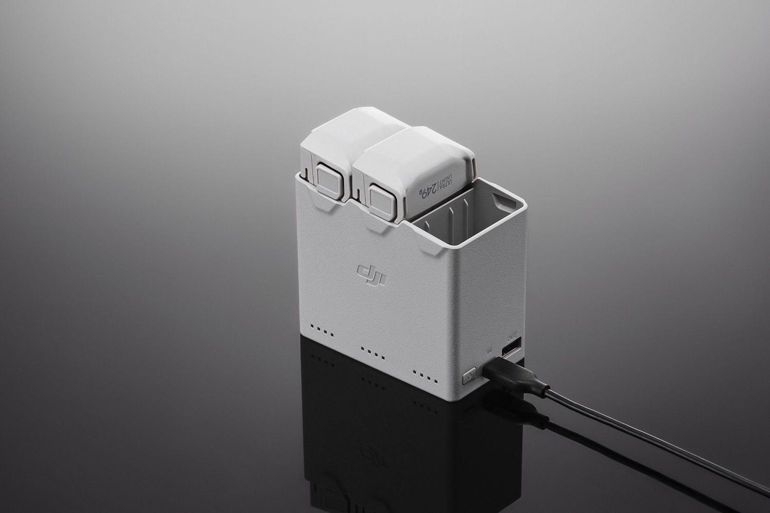 White and gray drone battery charger with two batteries.