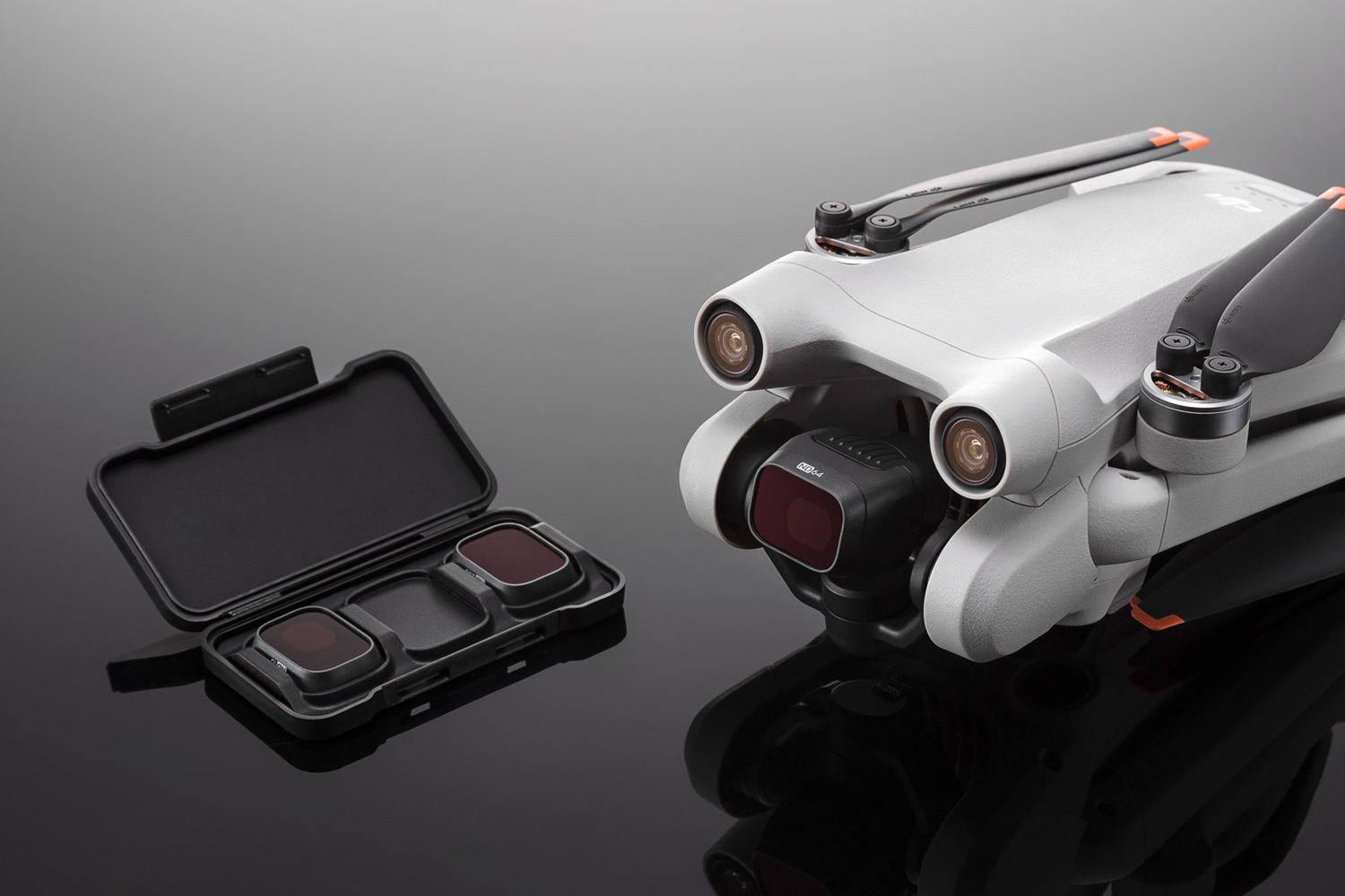Drone met filters in een koffer. Drone is zilver en zwart met drie zichtbare lenzen. Koffer bevat drie filters.