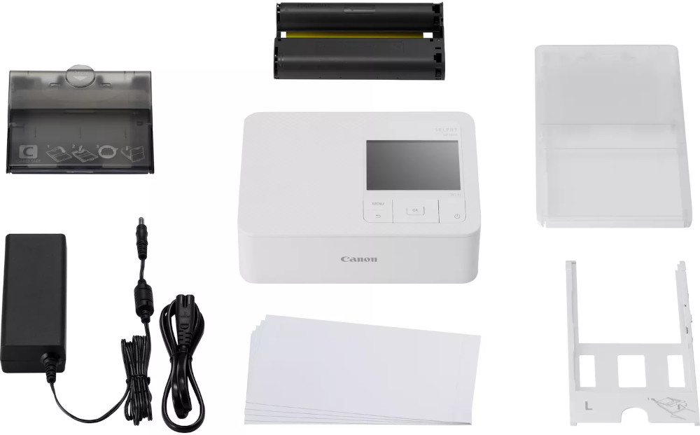 Une imprimante Canon Selphy avec cartouches, alimentation et papier.