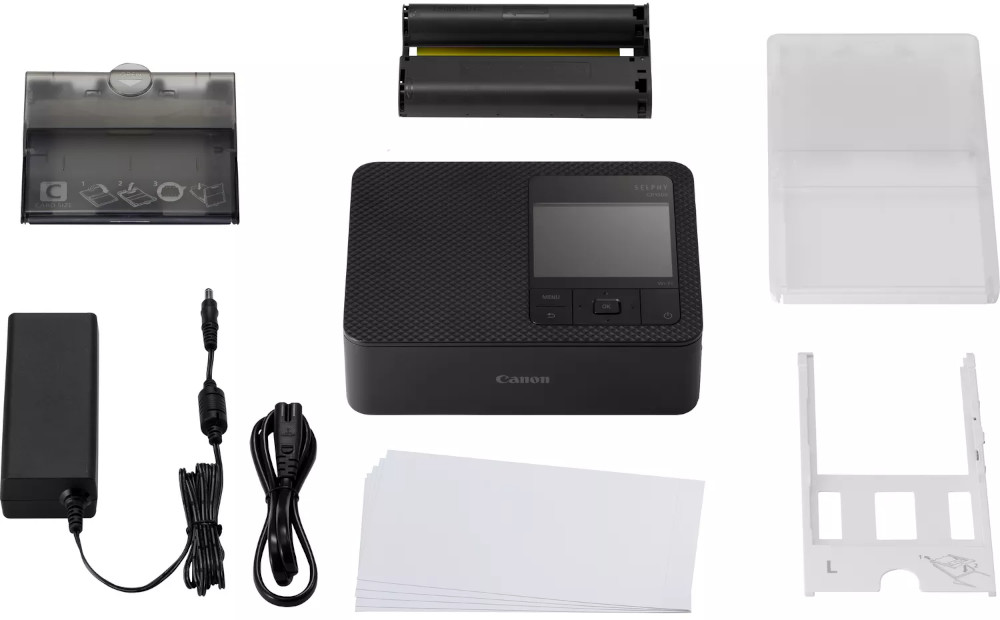 A Canon printer and accessories: power supply, paper, and black ink cartridges.