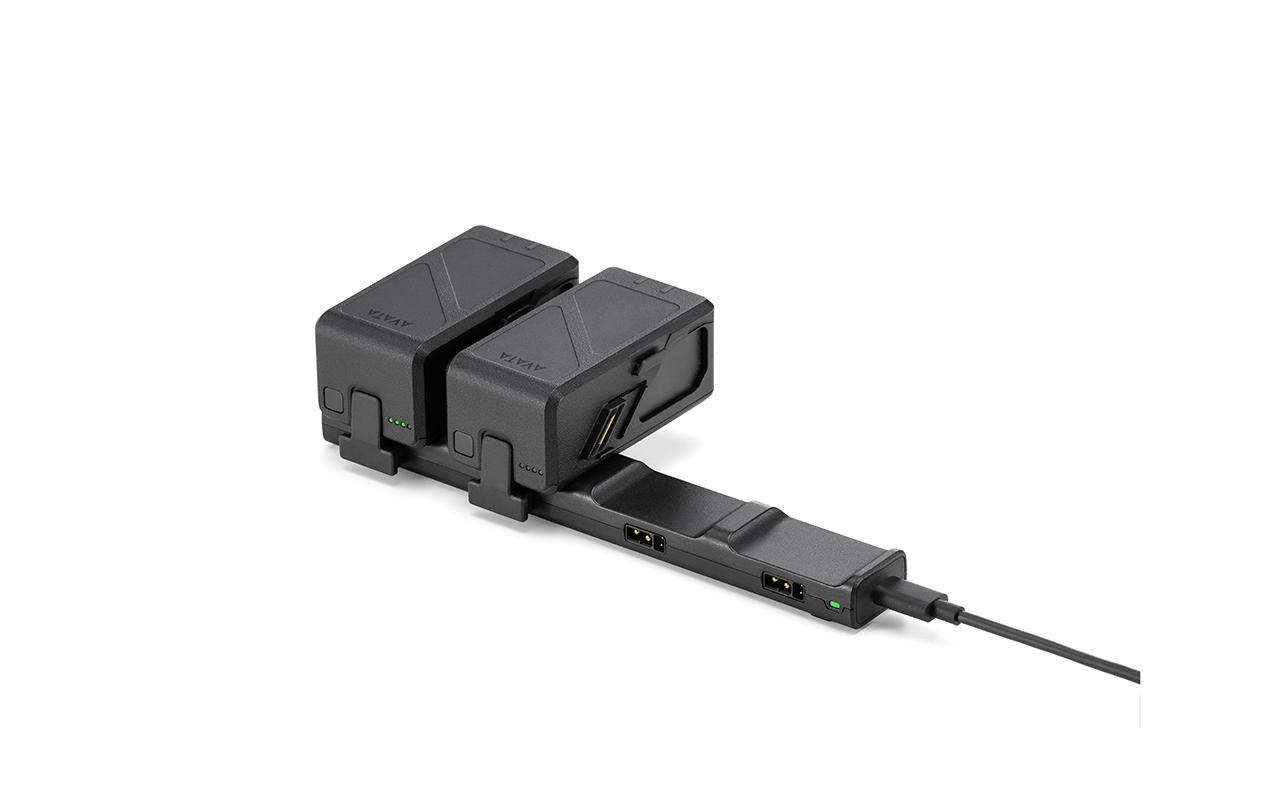 Schwarze Drohnen-Akkuladestation. Zwei Akkus und ein USB-Kabel. Weißer Hintergrund, schräge Ansicht.