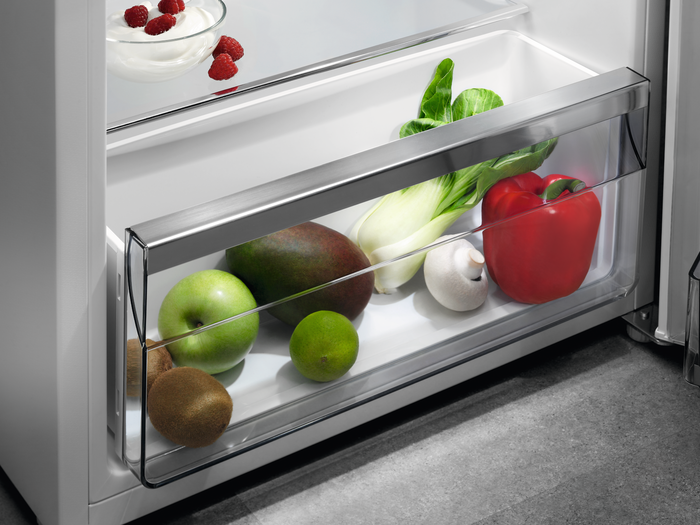 Un tiroir de réfrigérateur avec des fruits et légumes: pomme, citron vert, mangue, poivron, etc.