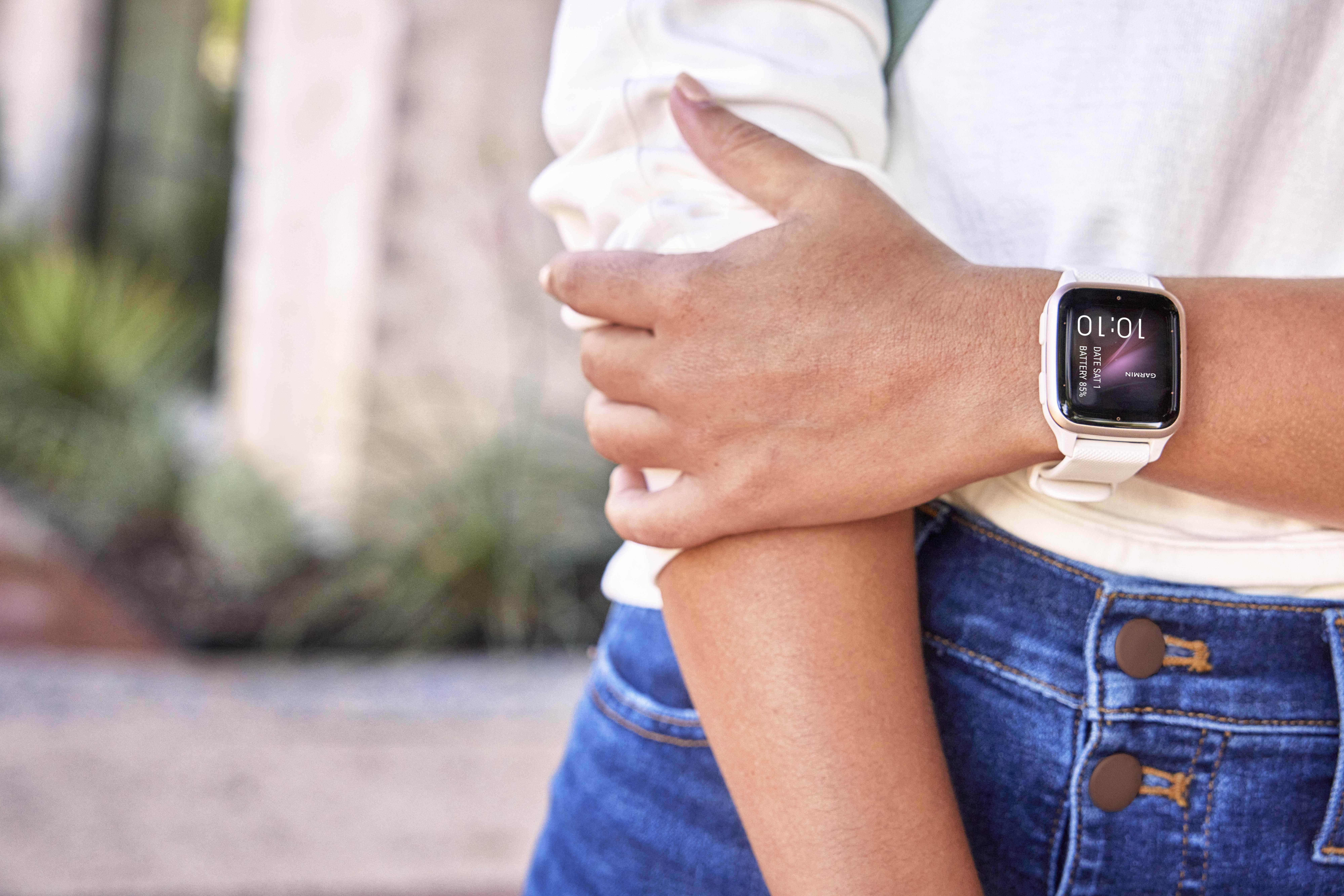 Das Handgelenk einer Person mit einer weißen Uhr. Die Uhr zeigt Zeit und andere Daten an.