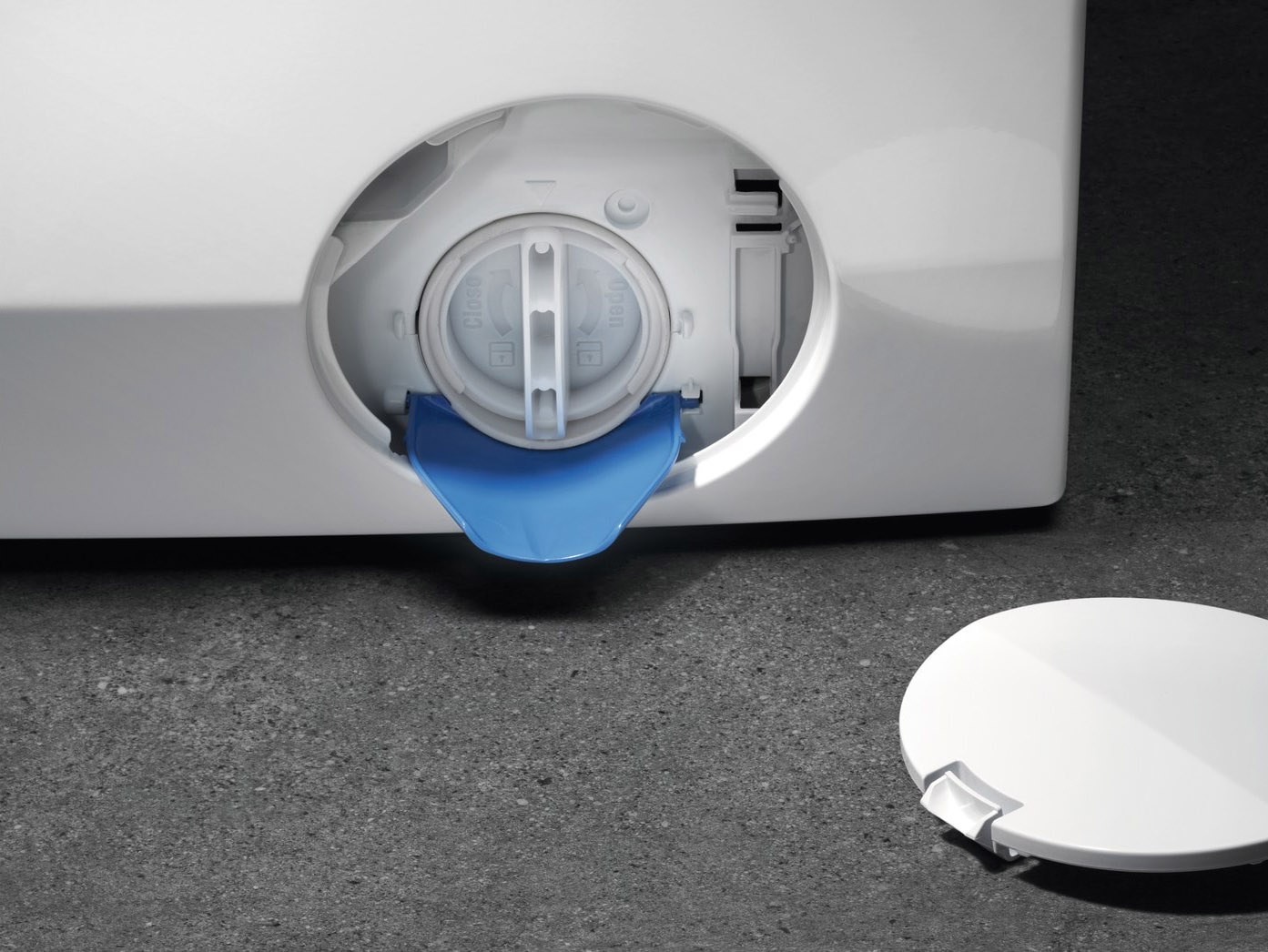 Close-up of a washing machine's drain. It has a blue cover and a white cap.