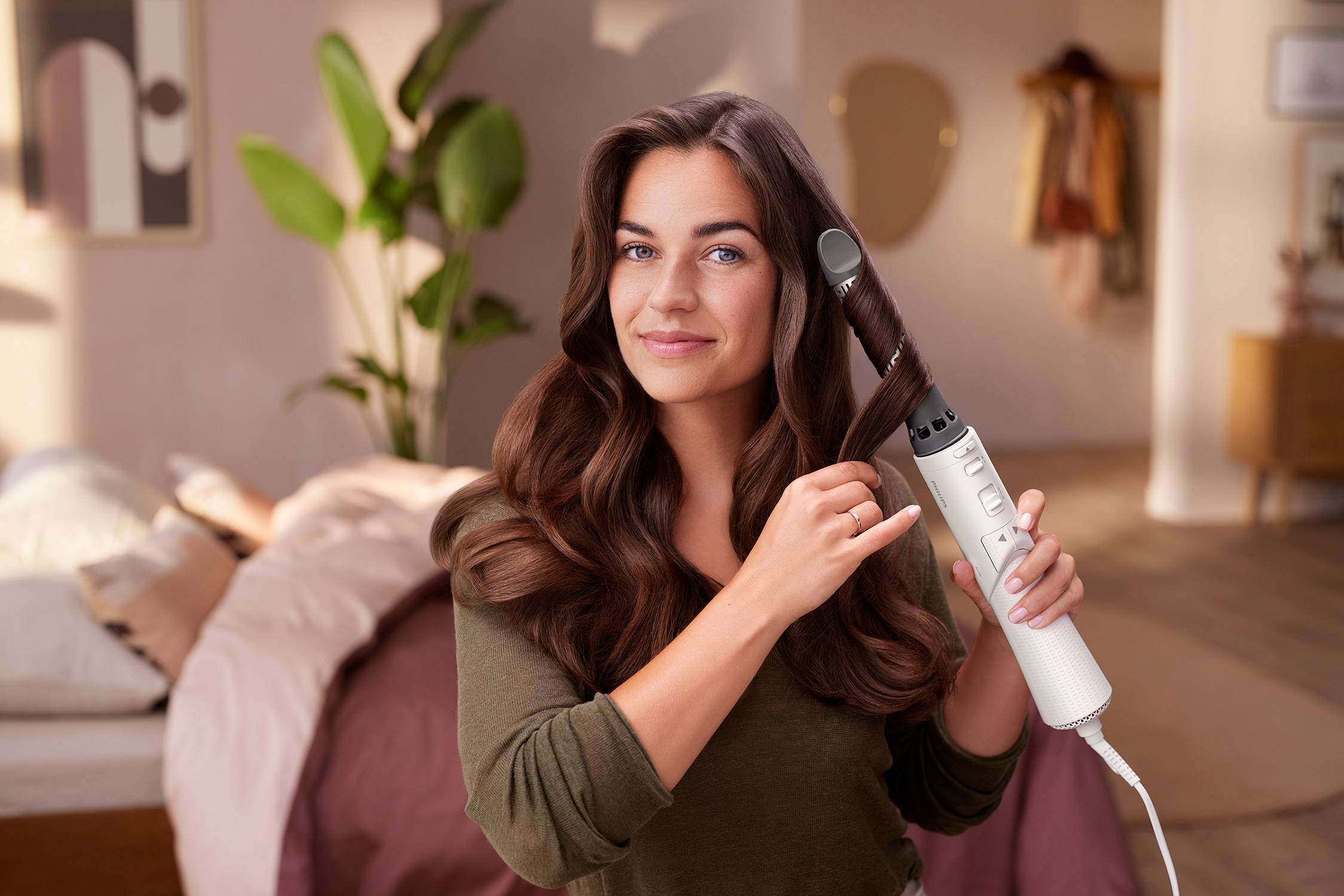 A woman curling her hair with a styler.