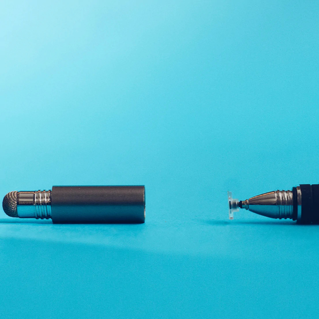 Deux stylets sur une surface bleue, un démonté avec une pointe et une partie métallique.