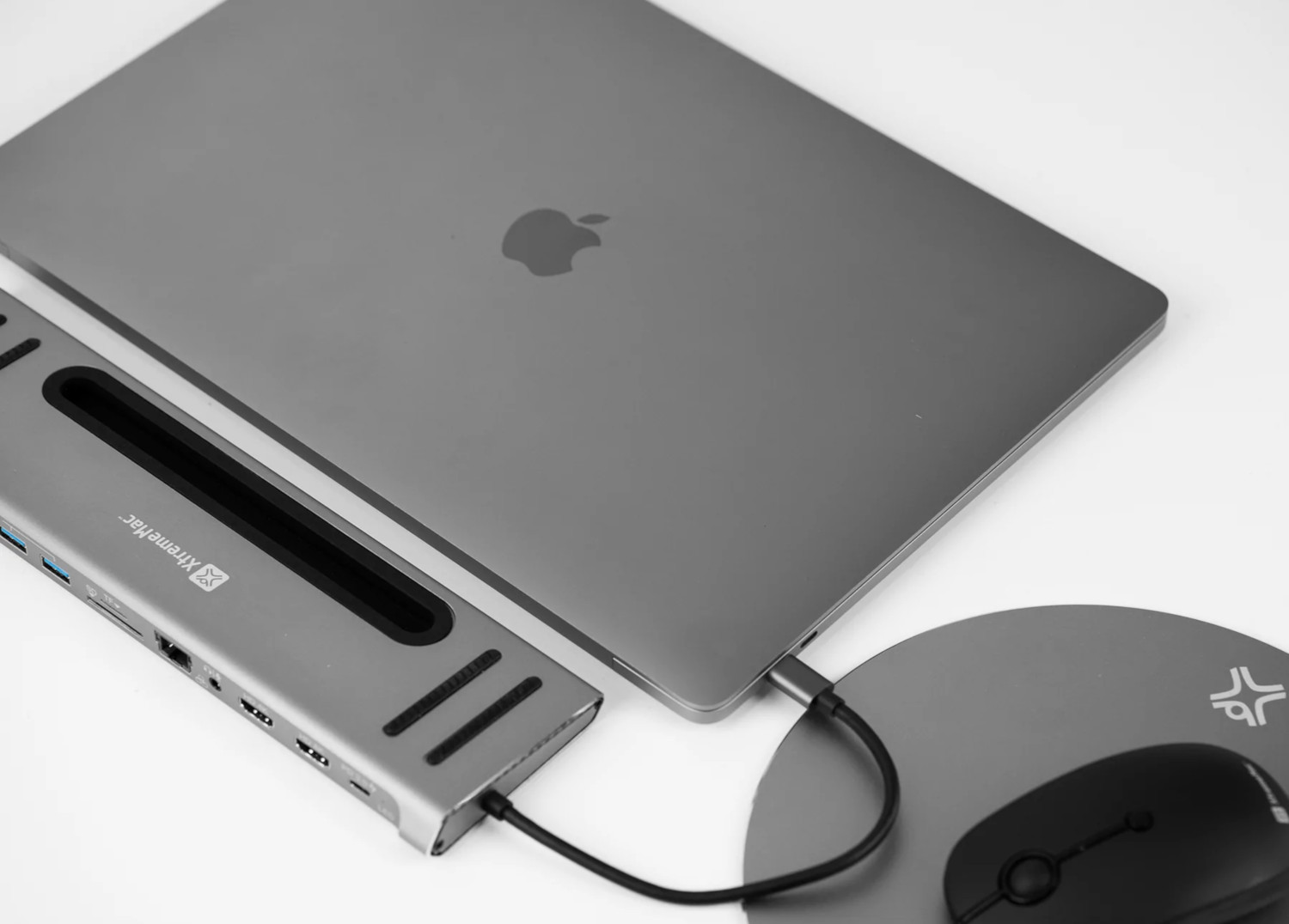 Ordinateur portable connecté à un hub et une souris sur une surface blanche.