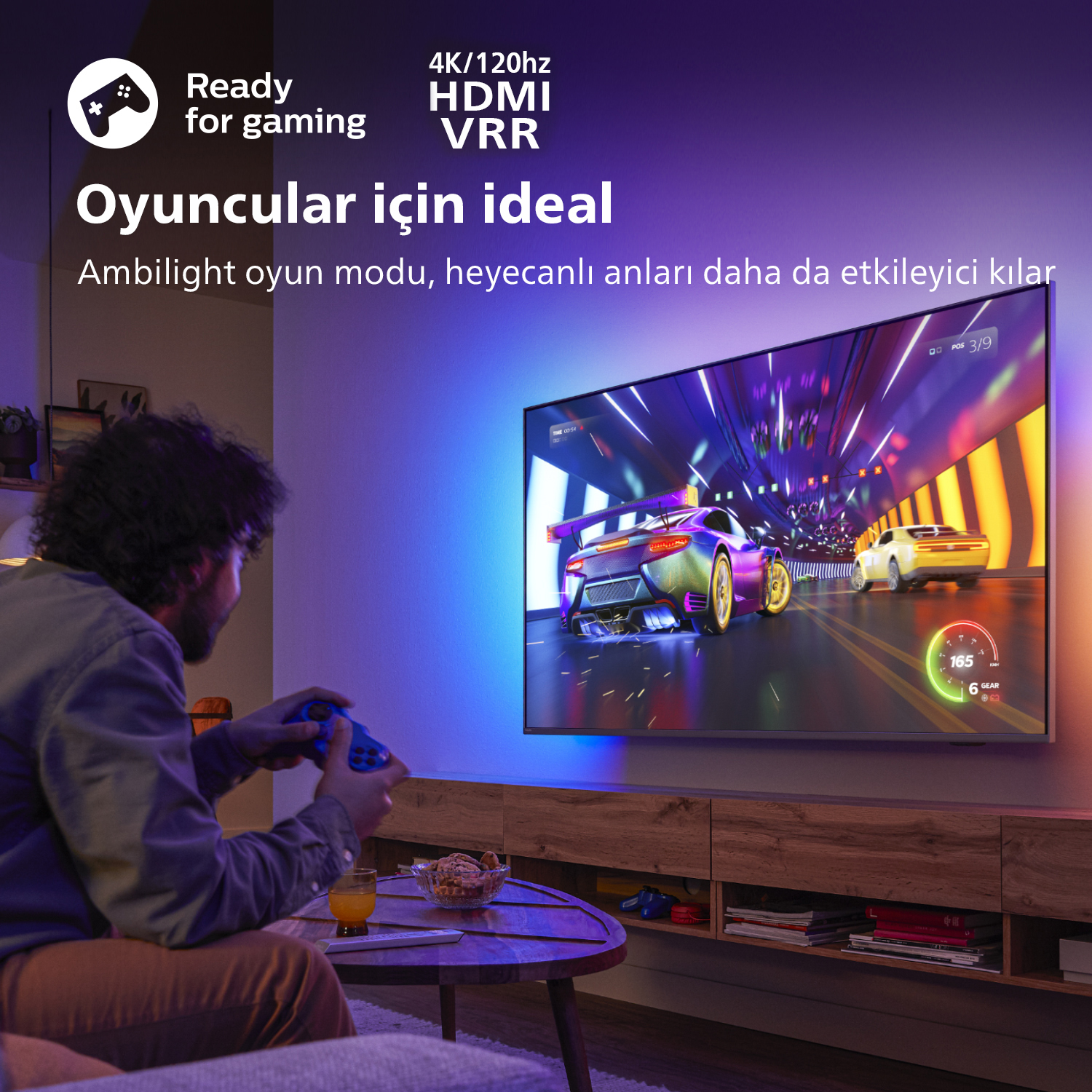 Adam TV'de video oyunu oynuyor; metin 'Oyun oynamaya hazır' ve 'Oyuncular için ideal' diyor.