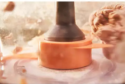 An orange blade inside a food processor chopping food, close-up view.