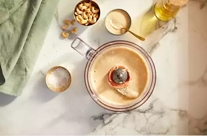 A food processor with ingredients for making cashew cream, top down view.