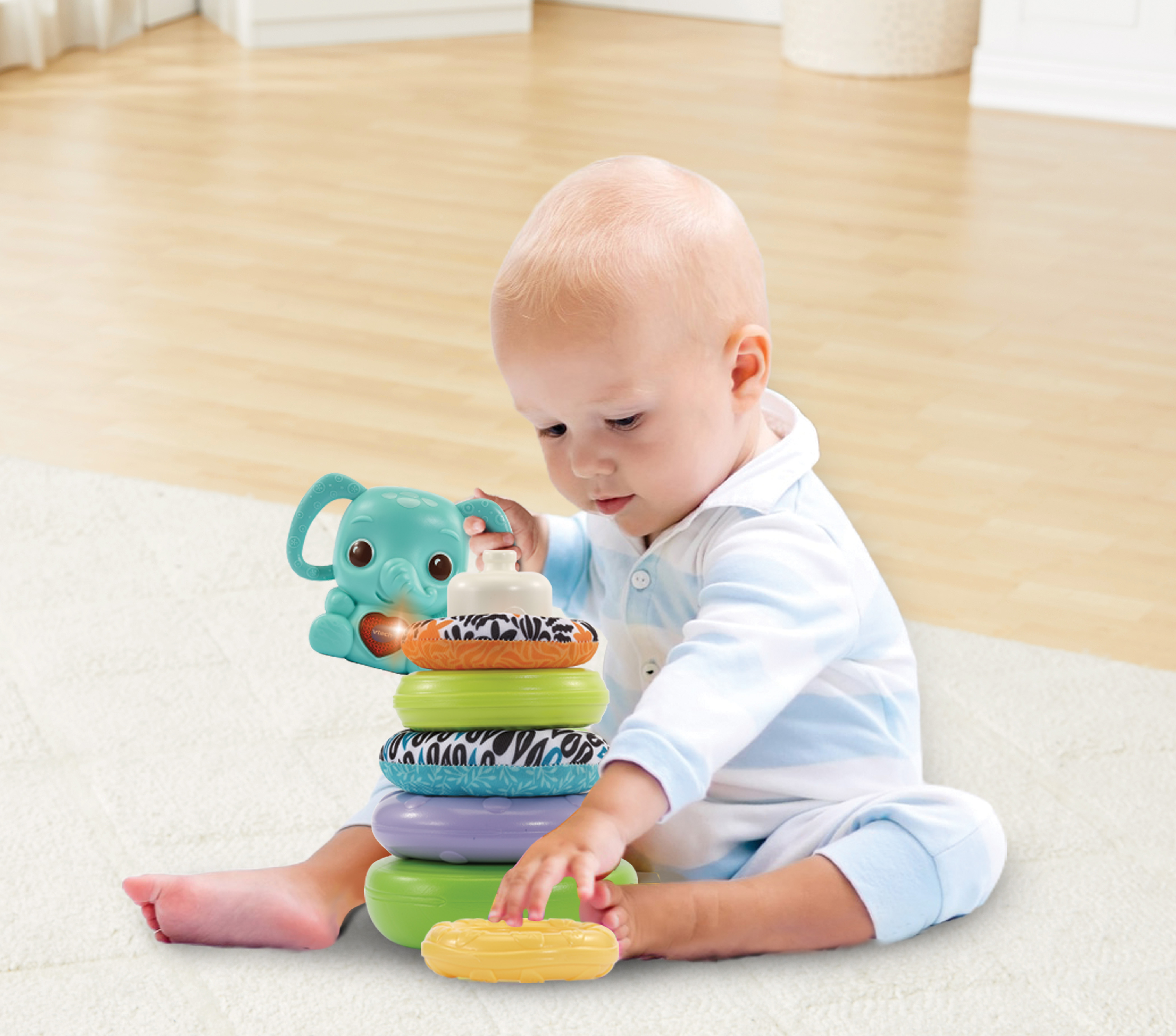 Baby spielt mit Stapelringen. Das Spielzeug hat einen Elefanten oben drauf.