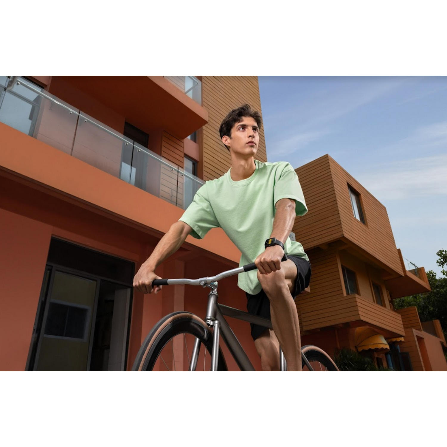 Un hombre montando en bicicleta en un día soleado, con una camisa verde y pantalones cortos negros.