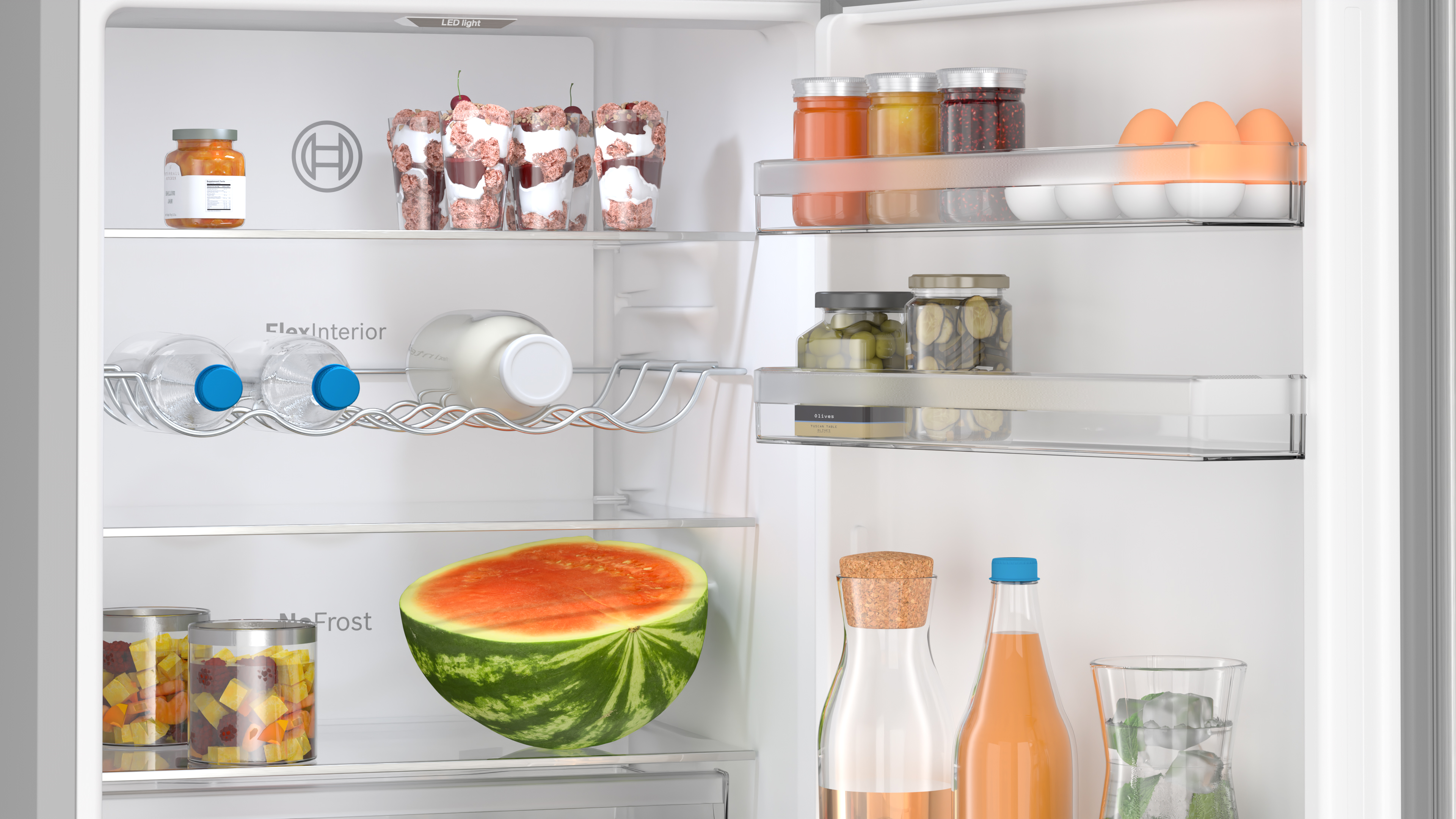 Im Inneren eines Kühlschranks mit verschiedenen Lebensmitteln: Gläser, Flaschen, Wasser, Obst und Eier.
