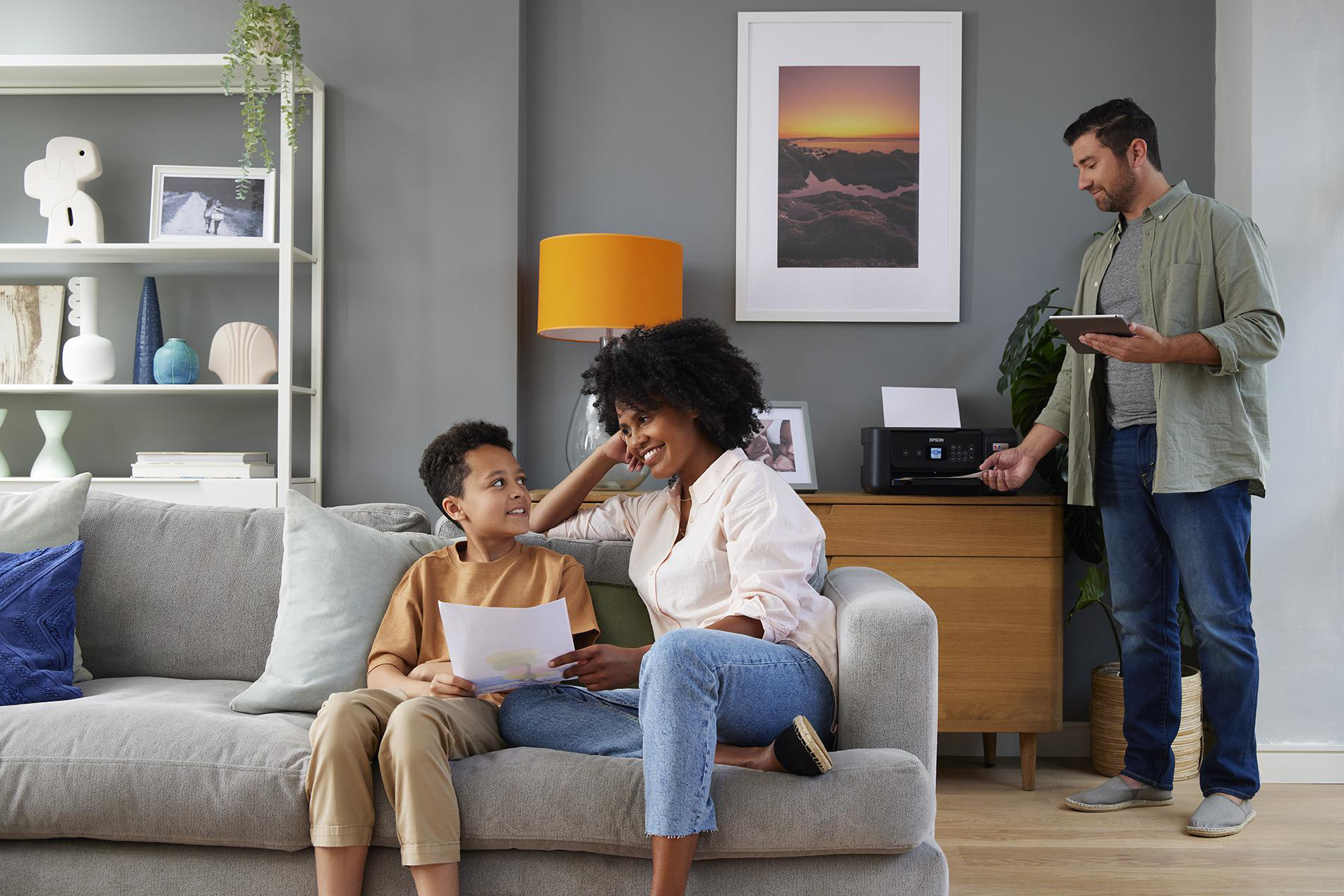 Familie im Wohnzimmer mit Drucker und Dokumenten.