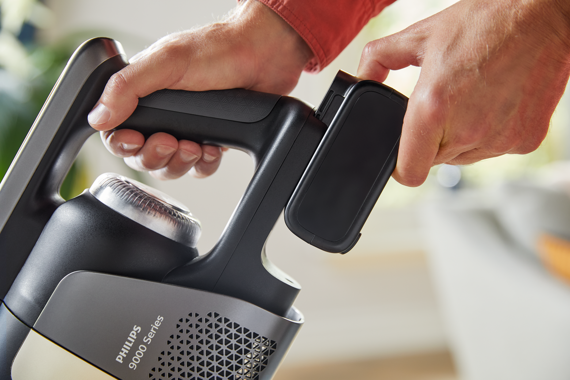 Person's hands holding vacuum cleaner handle.