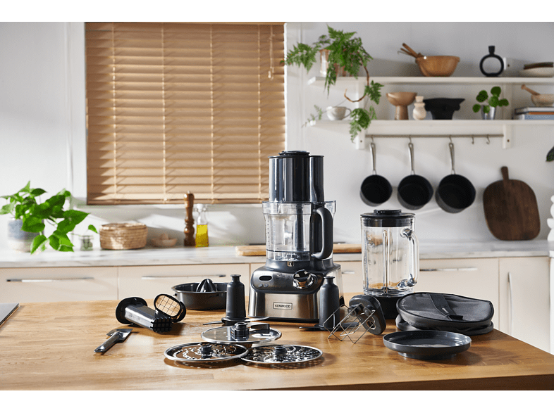 Scène de cuisine, robot culinaire et accessoires sur la table.