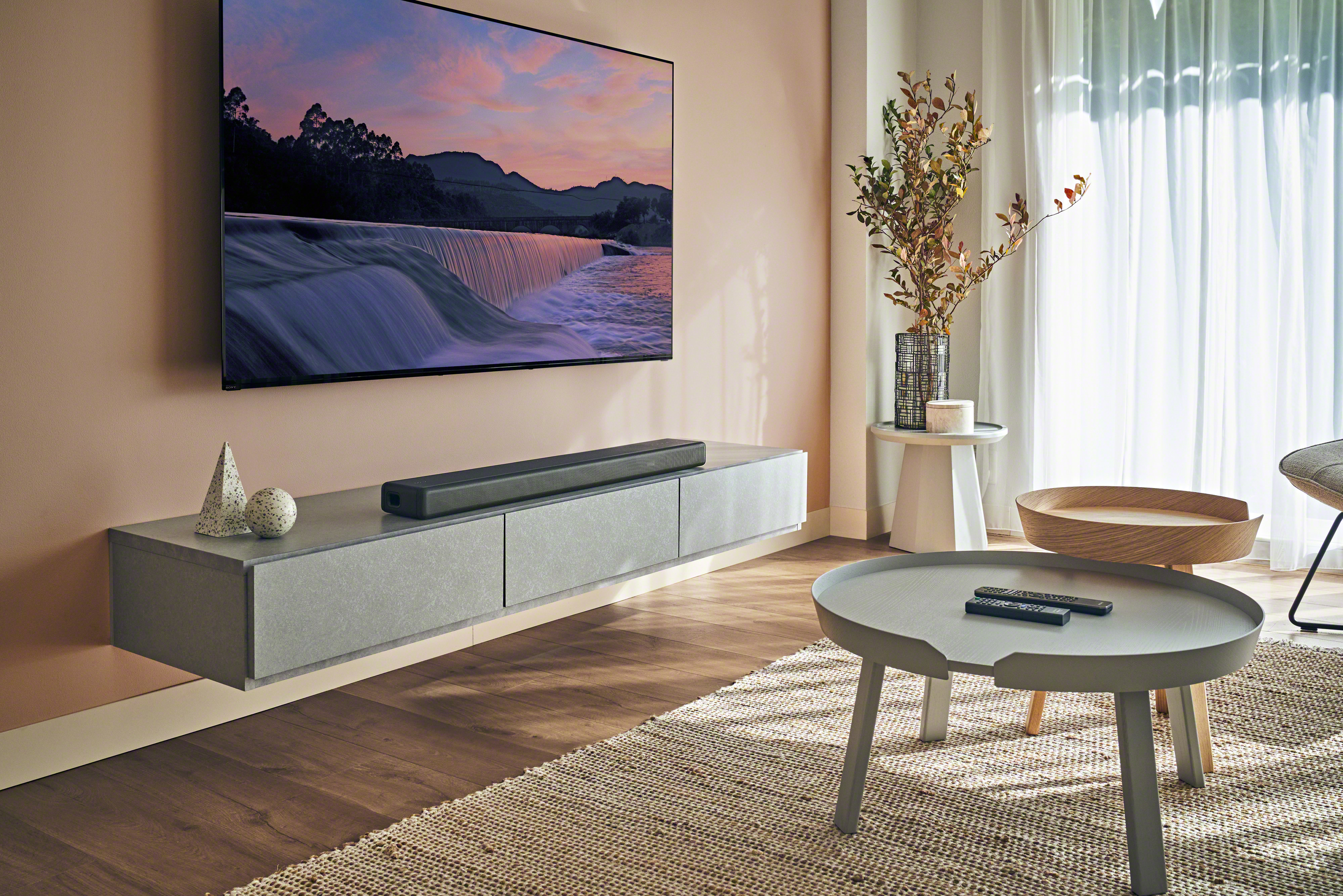 Un salon avec une télévision murale, une barre de son et une table basse.