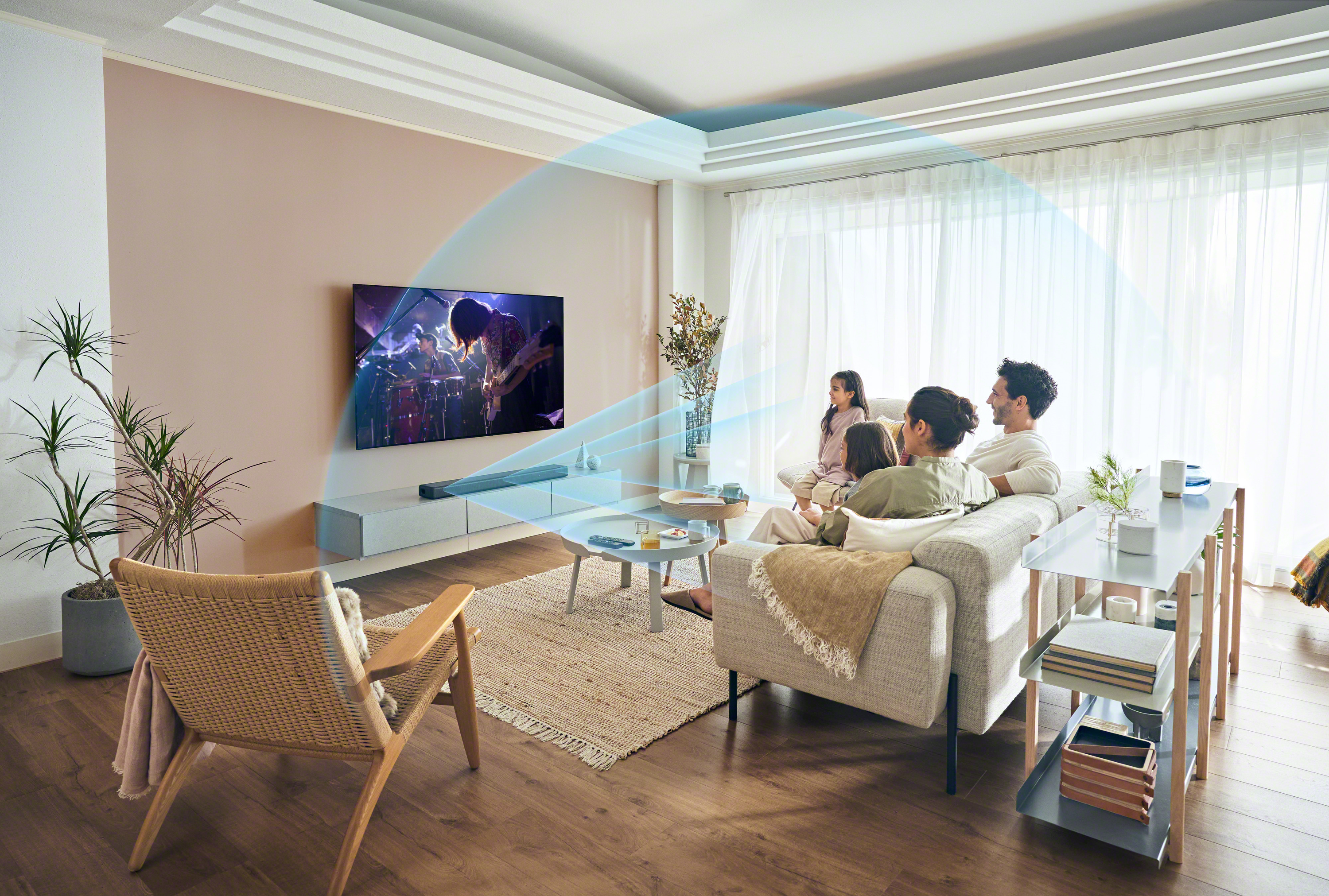 Des gens regardent la télévision dans un salon. La télévision montre un concert. Ondes sonores visualisées.