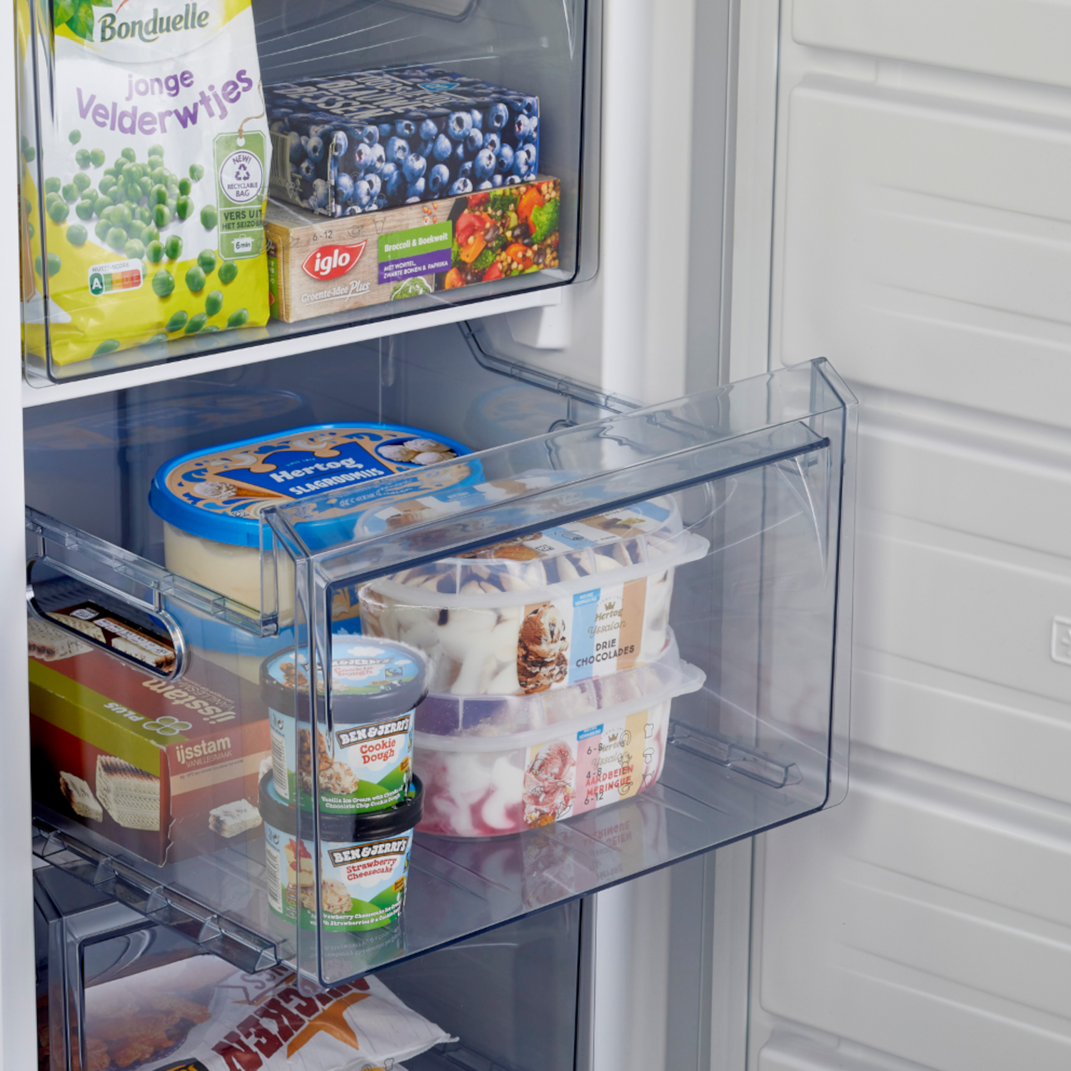 A refrigerator with frozen food items in clear drawers. Ice cream and vegetables are visible.