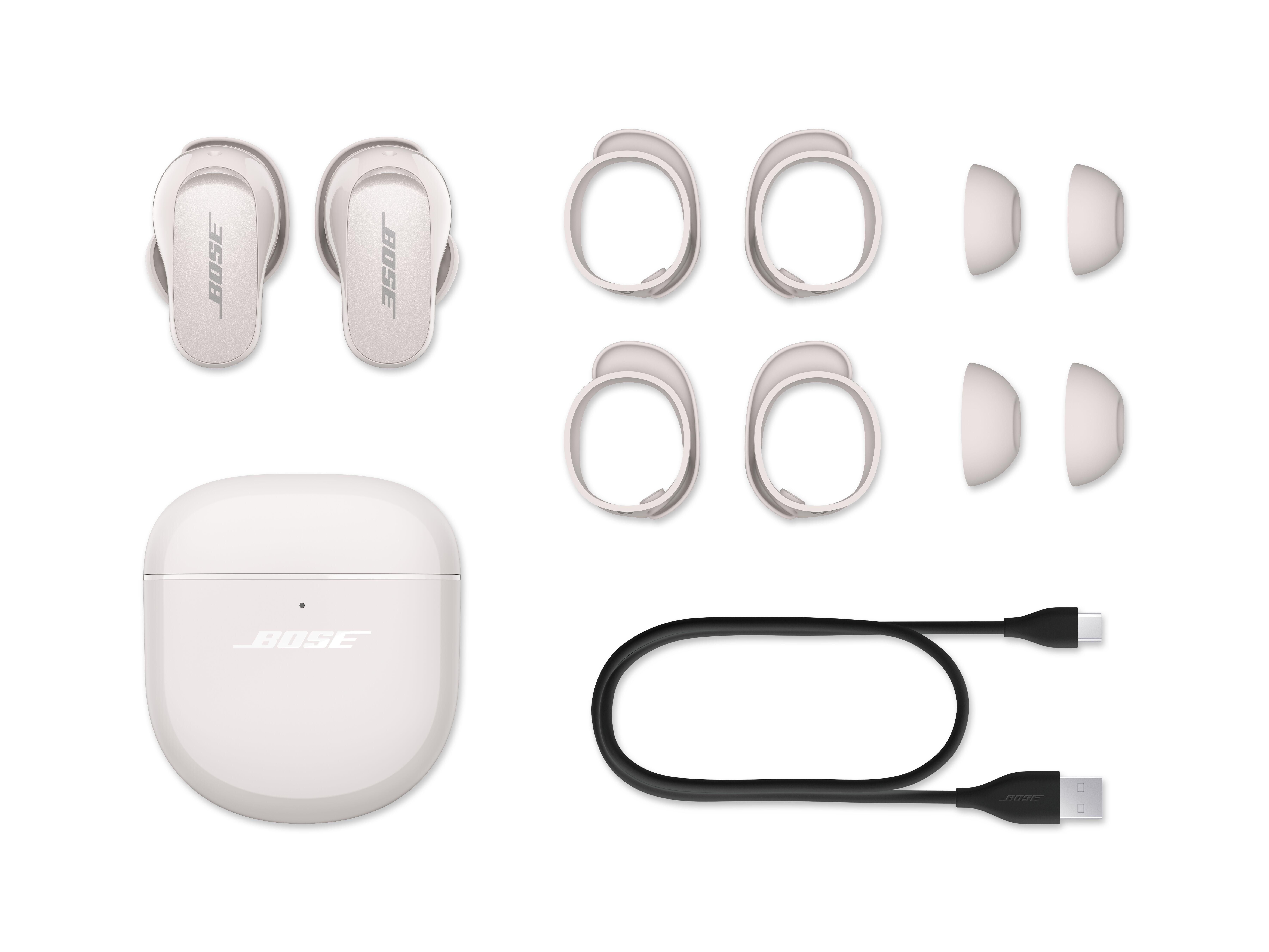 Weiße Bose-Ohrhörer, Hülle, Ohrstöpsel und ein Ladekabel auf weißem Hintergrund.