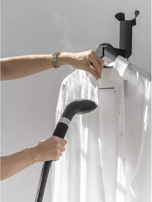 Personne repassant une chemise blanche avec un défroisseur noir.