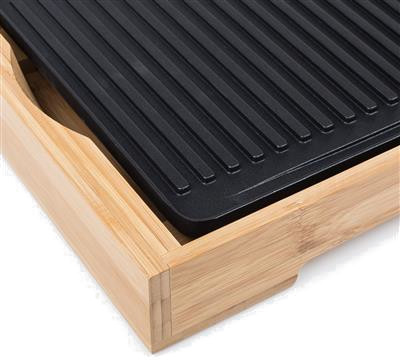 Plaque de grill noire encadrée de bois. Le grill a des lignes verticales.