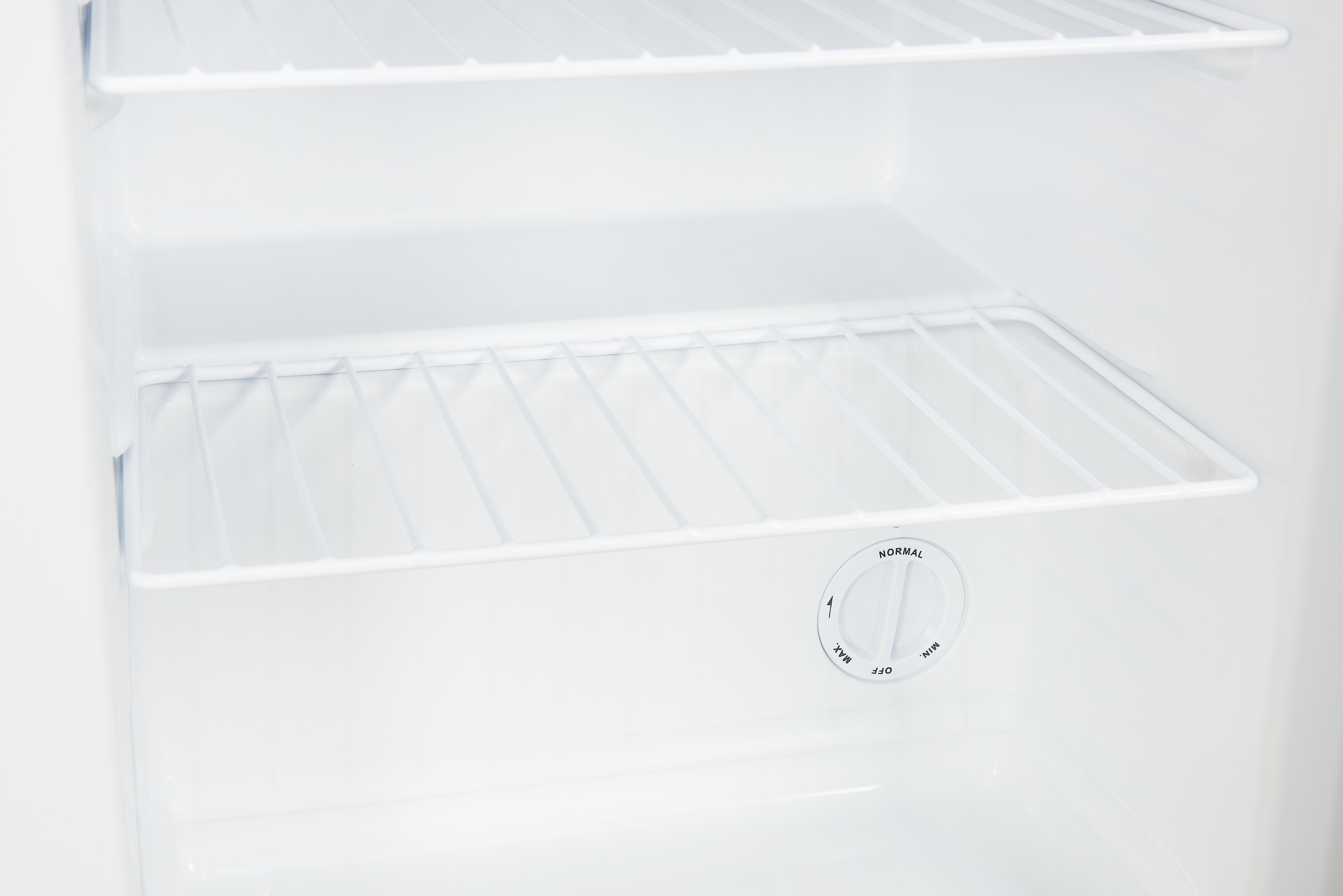 Im Inneren eines weißen Kühlschranks mit Regalen und einem Temperaturregler.