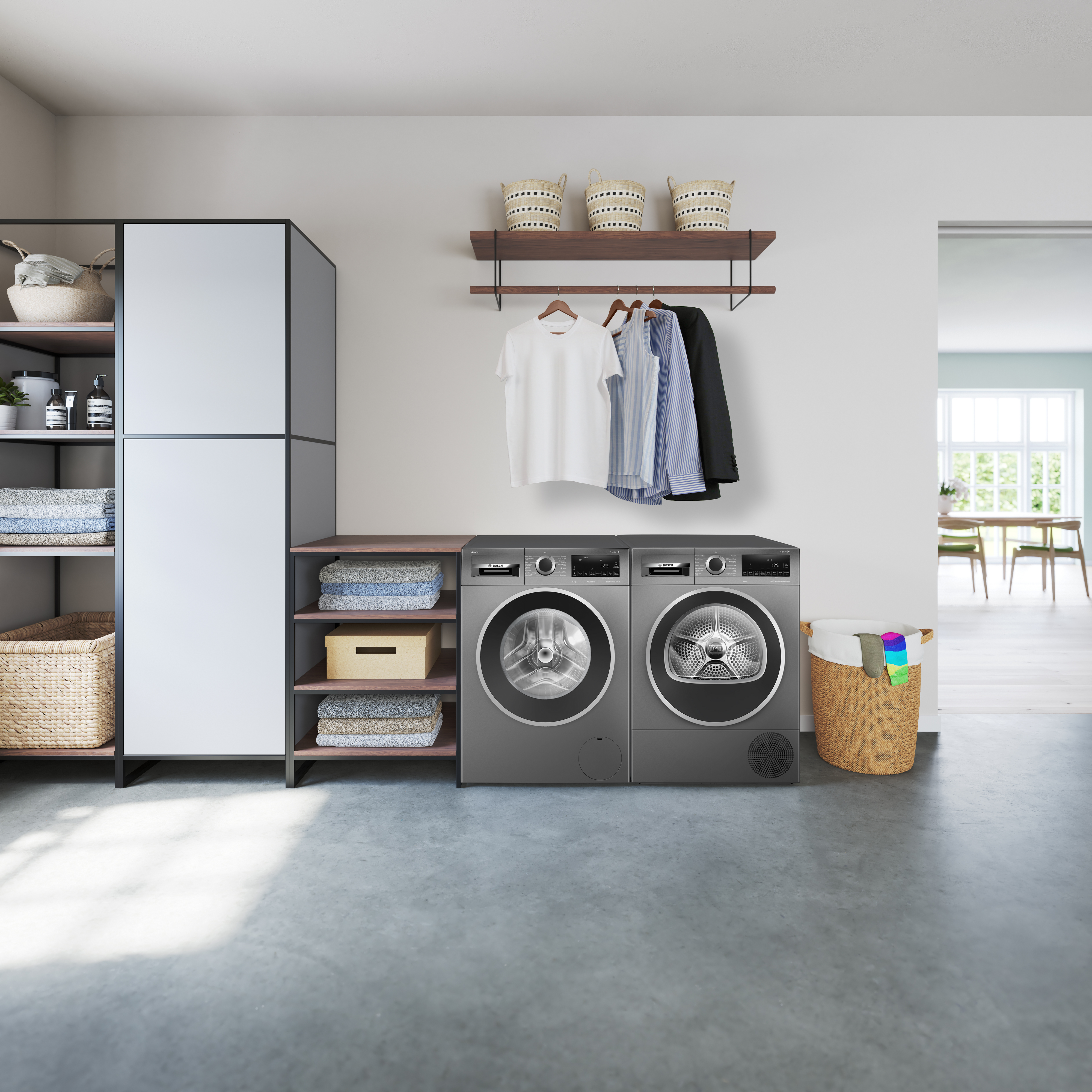 A laundry room with a washing machine, dryer, and storage shelves, with clothes.