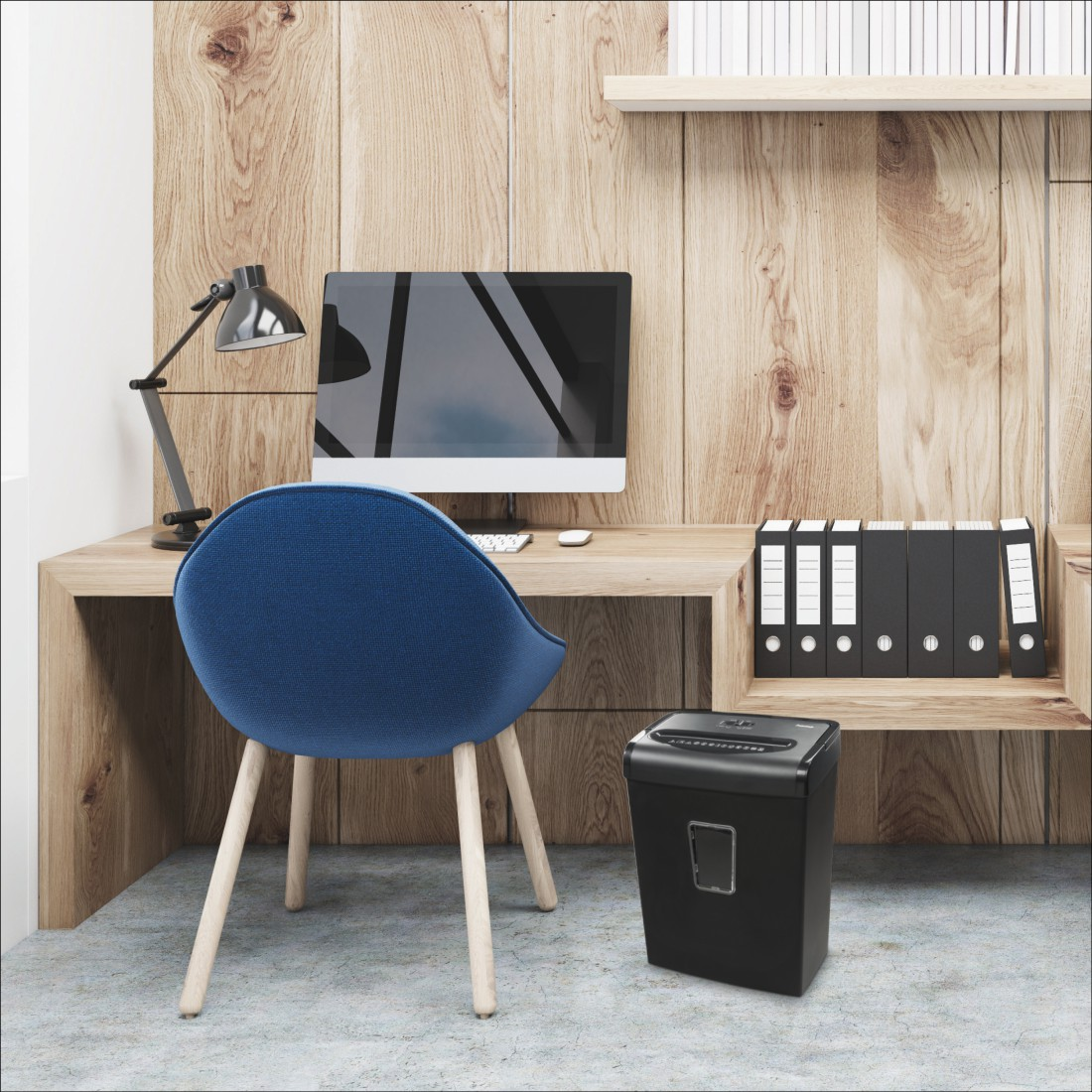 Schreibtischszene mit Monitor, Lampe, Stuhl und Aktenvernichter.