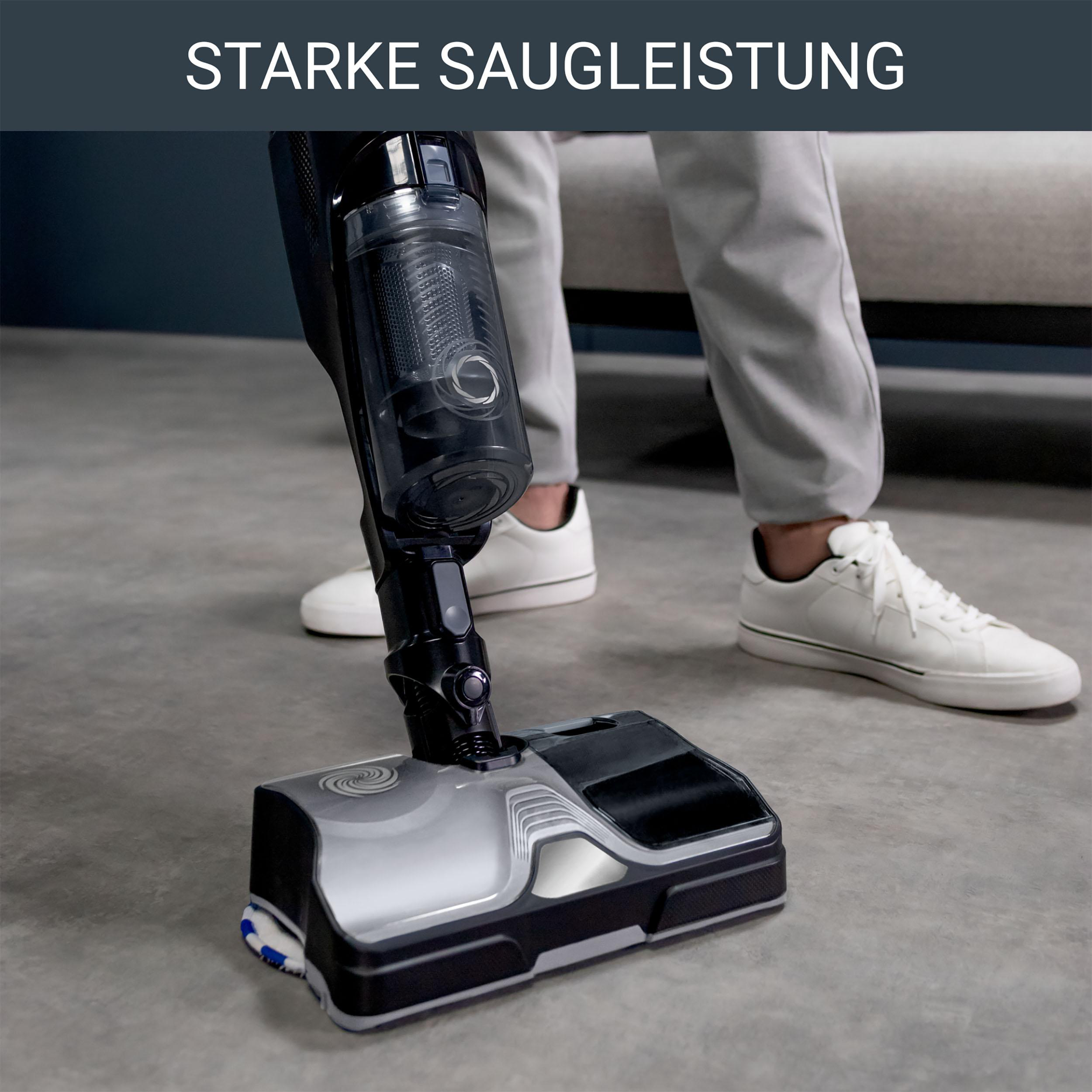 Eine Person, die einen schwarz-silbernen Staubsauger benutzt.