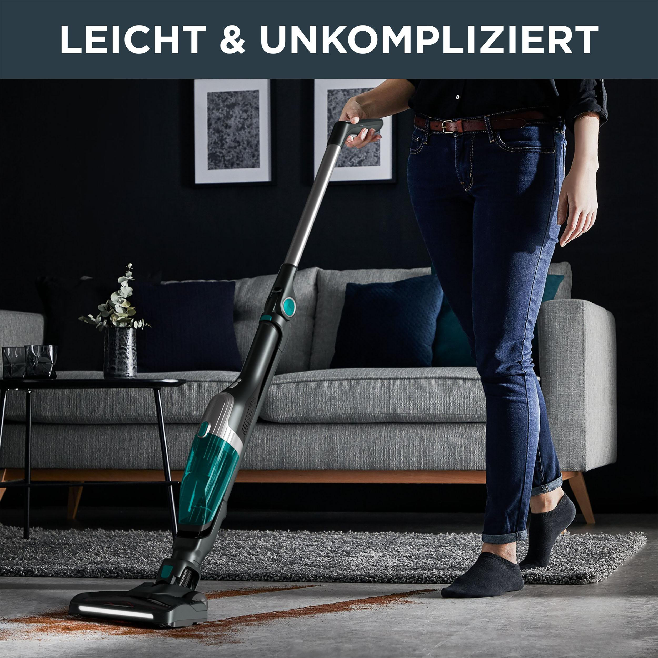 Frau, die einen Teppichboden mit einem kabellosen Staubsauger saugt, modernes Wohnzimmer.