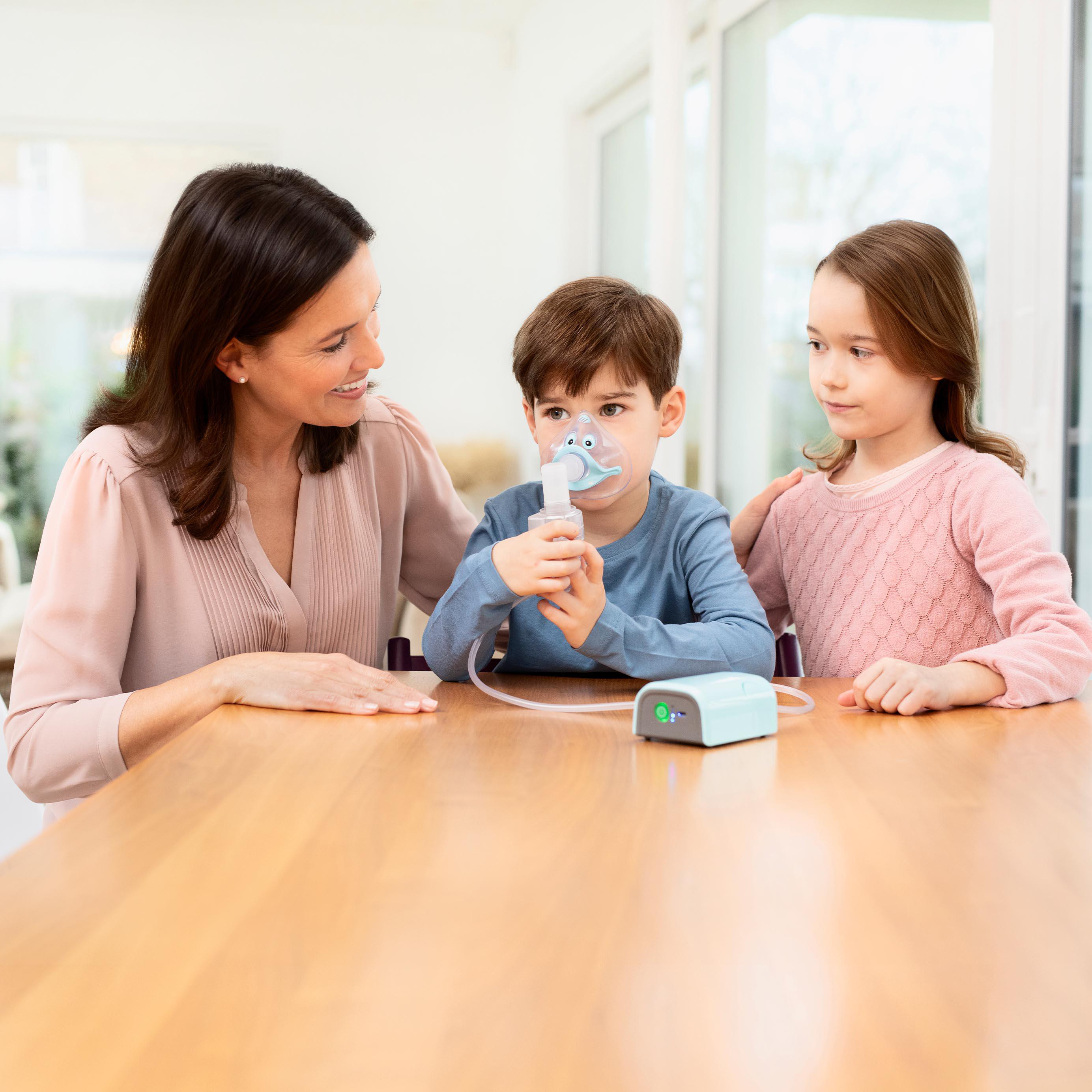 Eine Familie benutzt einen Vernebler. Eine Frau, ein Junge und ein Mädchen sind im Bild.