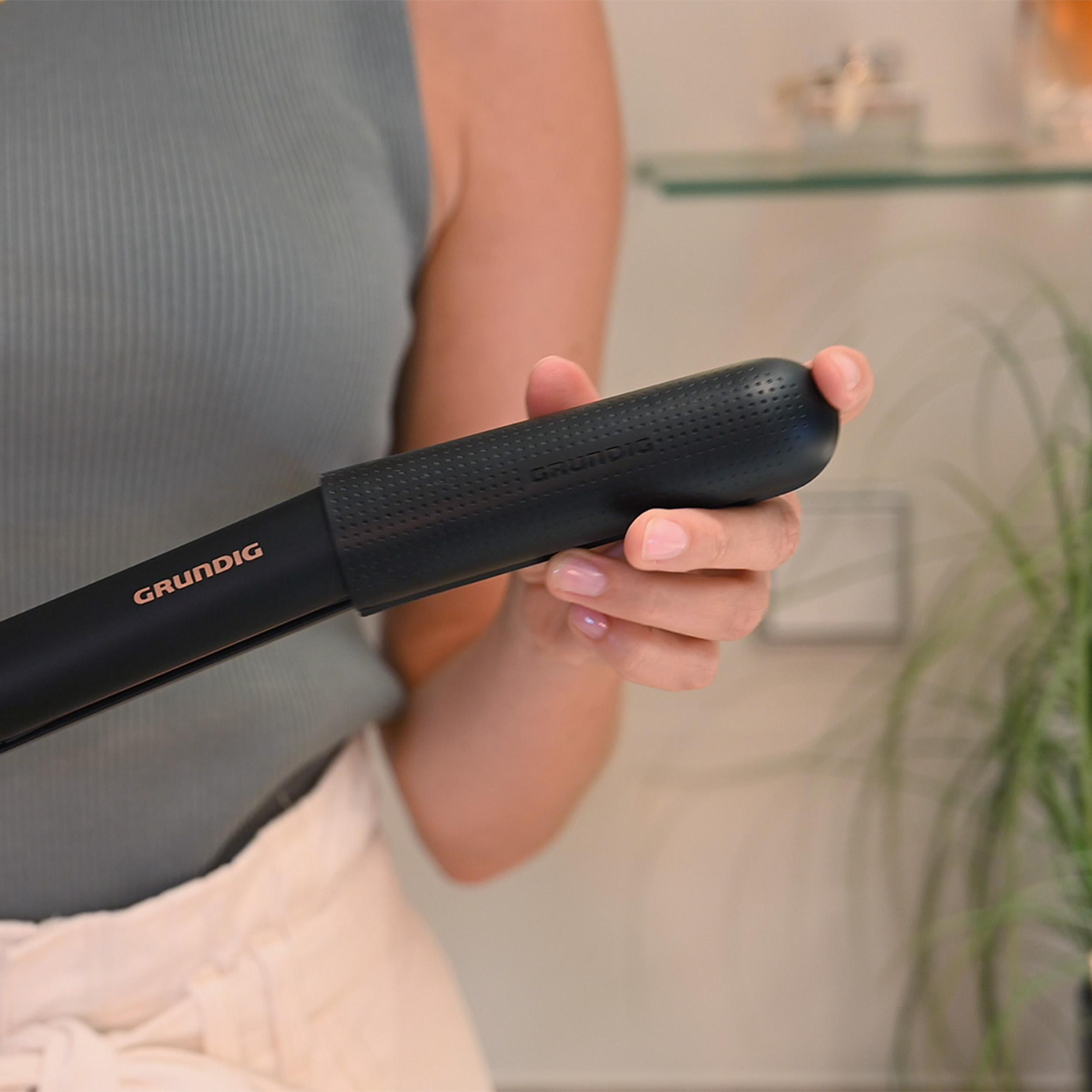 Eine Person hält eine schwarze Grundig Haarglättungsbürste.