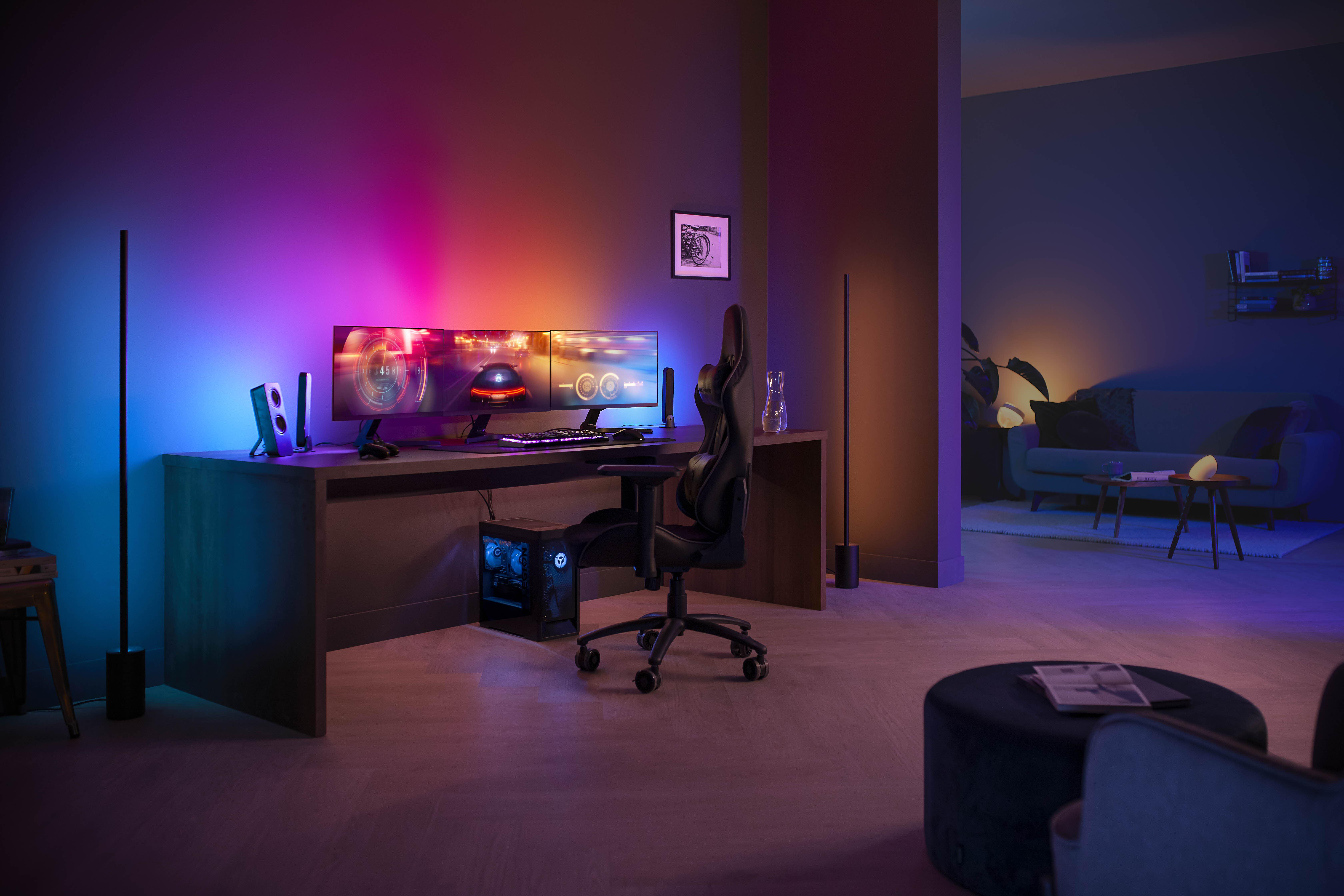 Ein modernes Gaming-Setup mit zwei Monitoren, Schreibtisch, Stuhl und Umgebungsbeleuchtung.