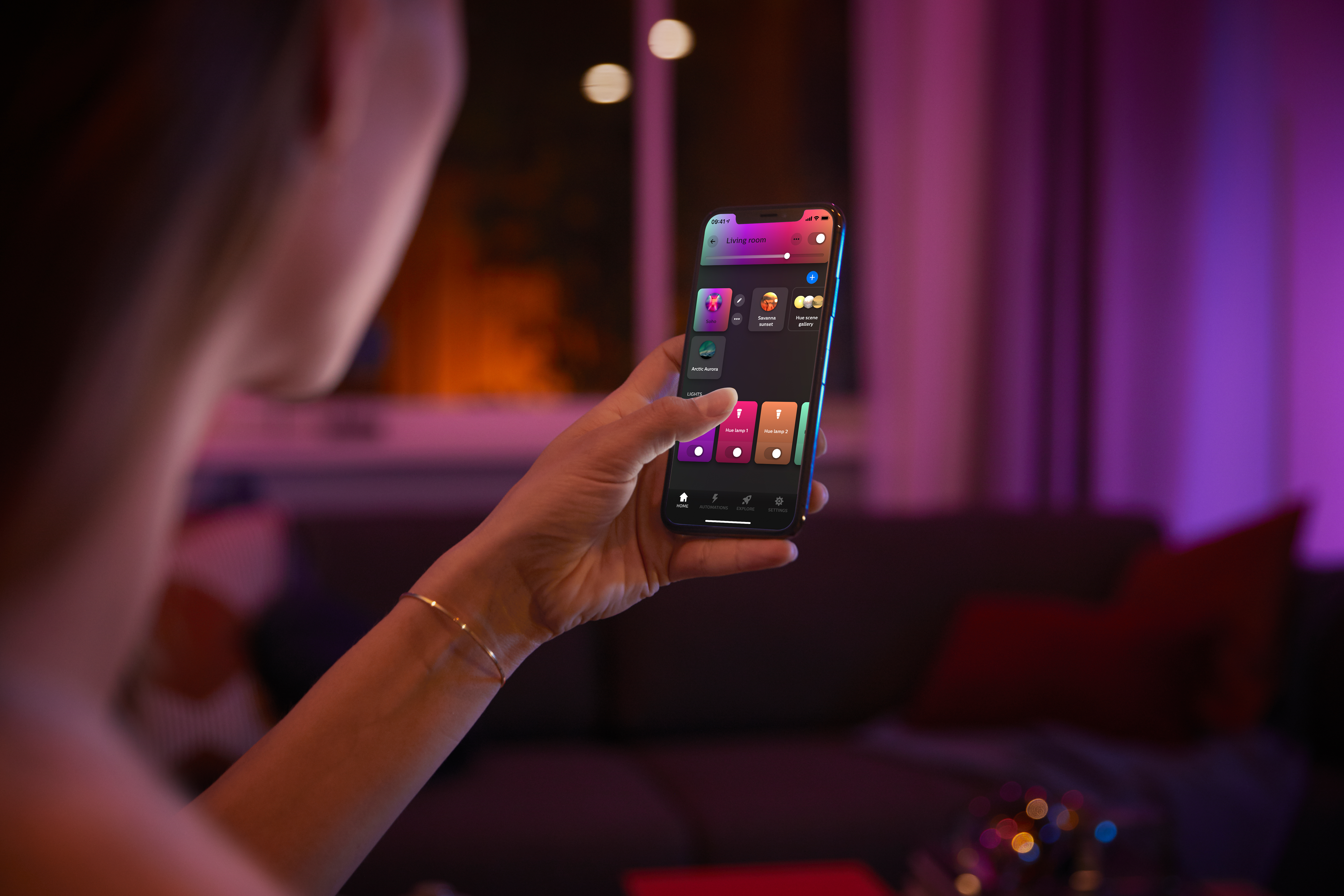 Eine Hand hält ein Smartphone mit einer App, die intelligente Lichter in einem Raum steuert.