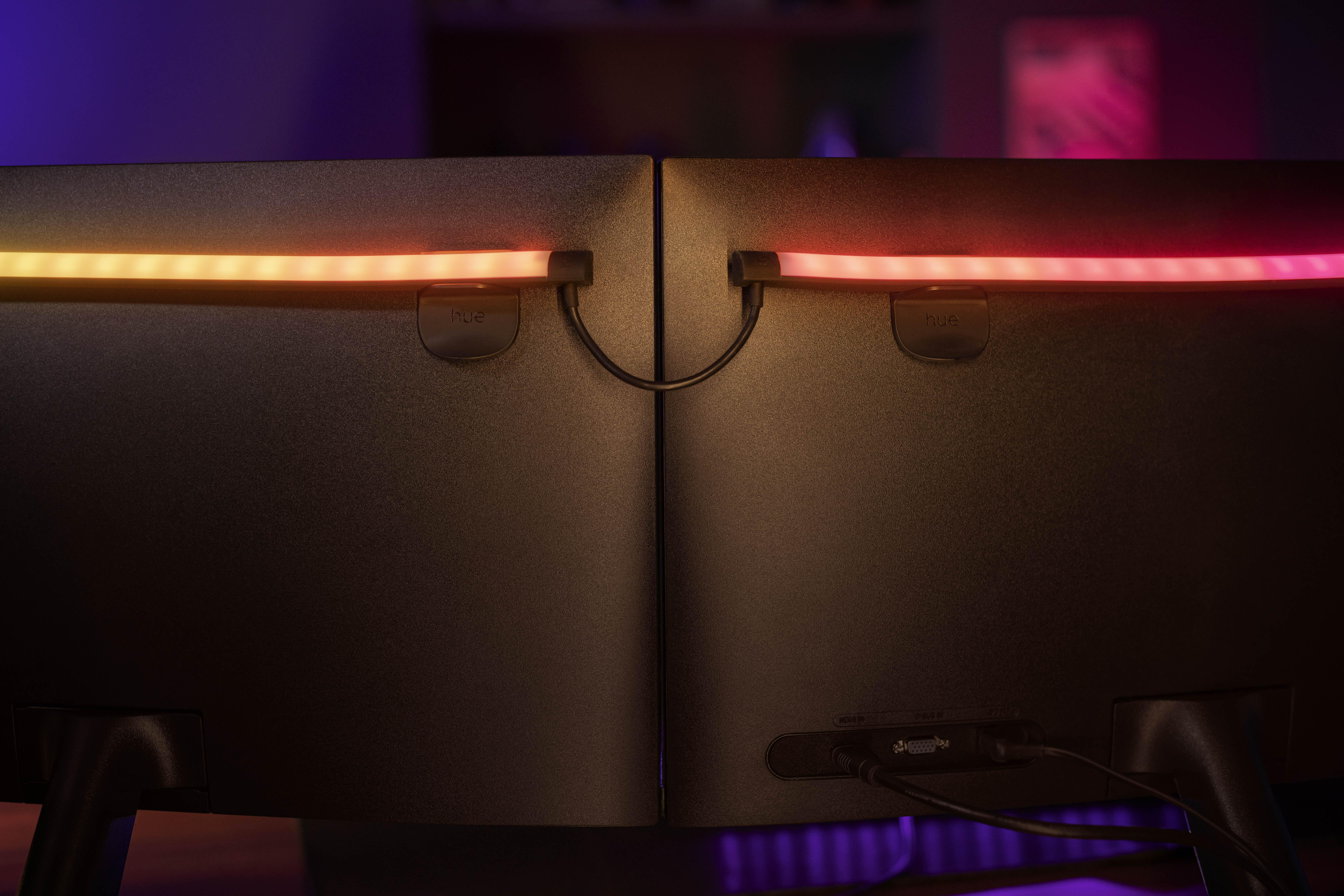 Zwei schwarze Computermonitore, verbunden mit einem farbenfrohen LED-Lichtstreifen.