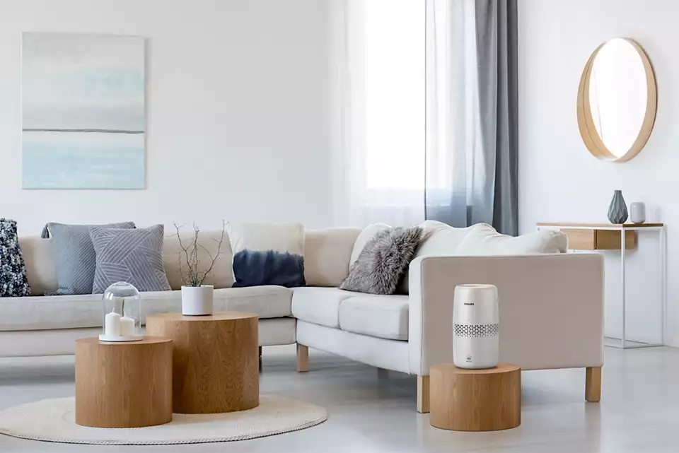 Wohnzimmer mit weißem Sofa, Holztischen und einem Gemälde.