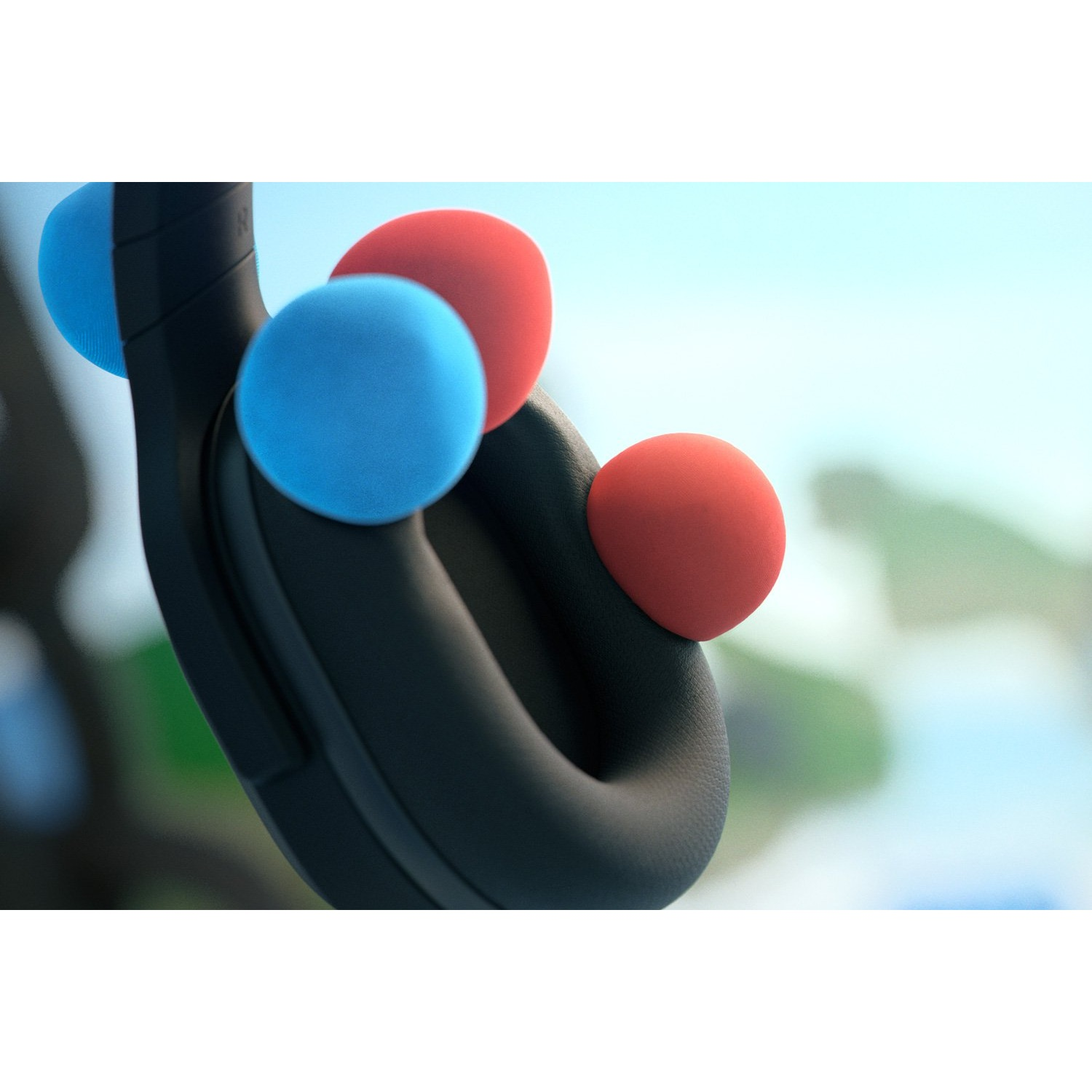 Primer plano de auriculares con tres bolas de colores. El fondo muestra un cielo borroso.