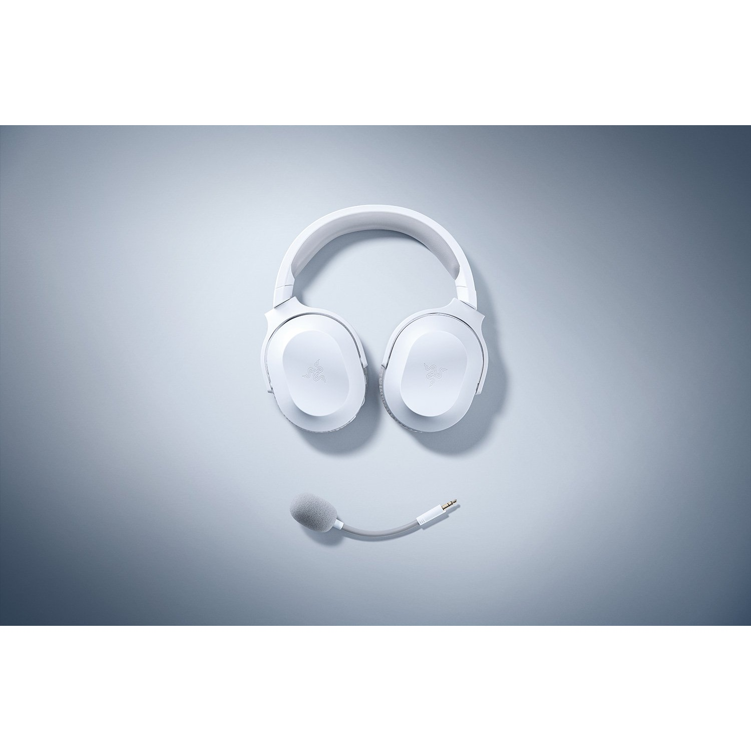 Auriculares blancos y un micrófono desmontable sobre un fondo azul claro, vista superior.