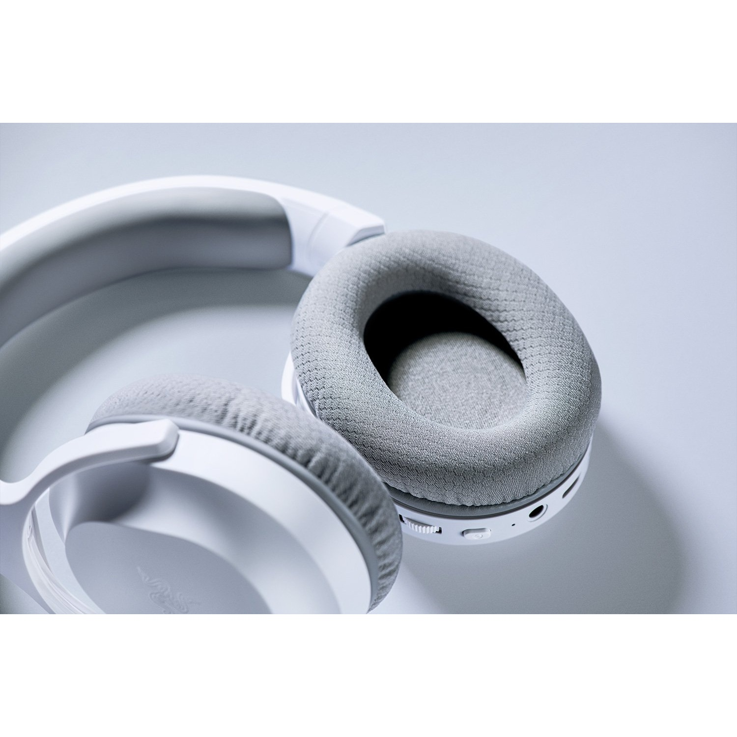 Auriculares blancos y grises sobre una superficie blanca. Las almohadillas son grises.