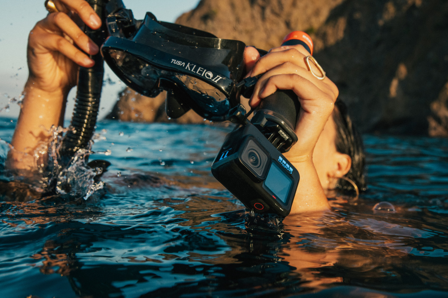 Person im Wasser, mit GoPro-Kamera und Schnorchelmaske, die eine Unterwasseransicht aufnimmt.