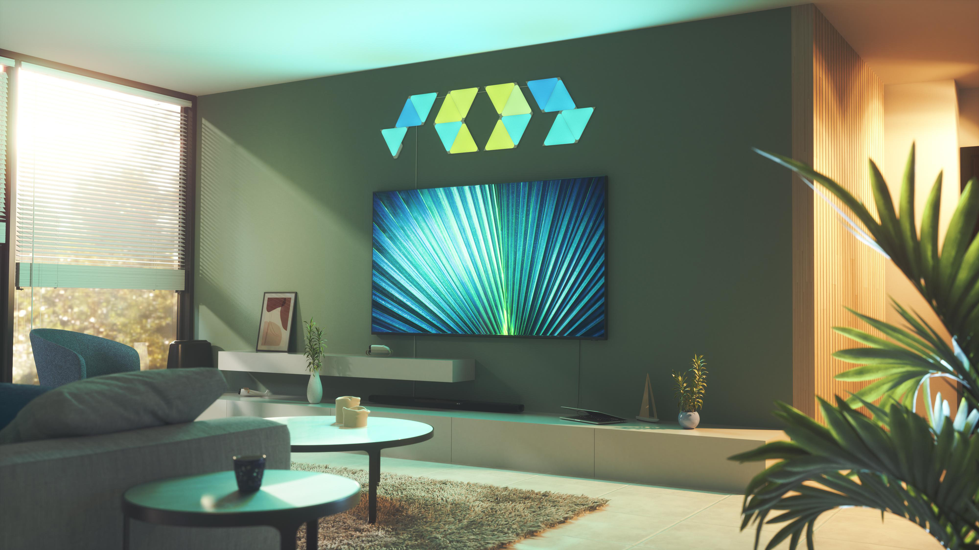 Ein Wohnzimmer mit Fernseher und grüner Wand. Über dem Fernseher befinden sich dekorative Lichter.