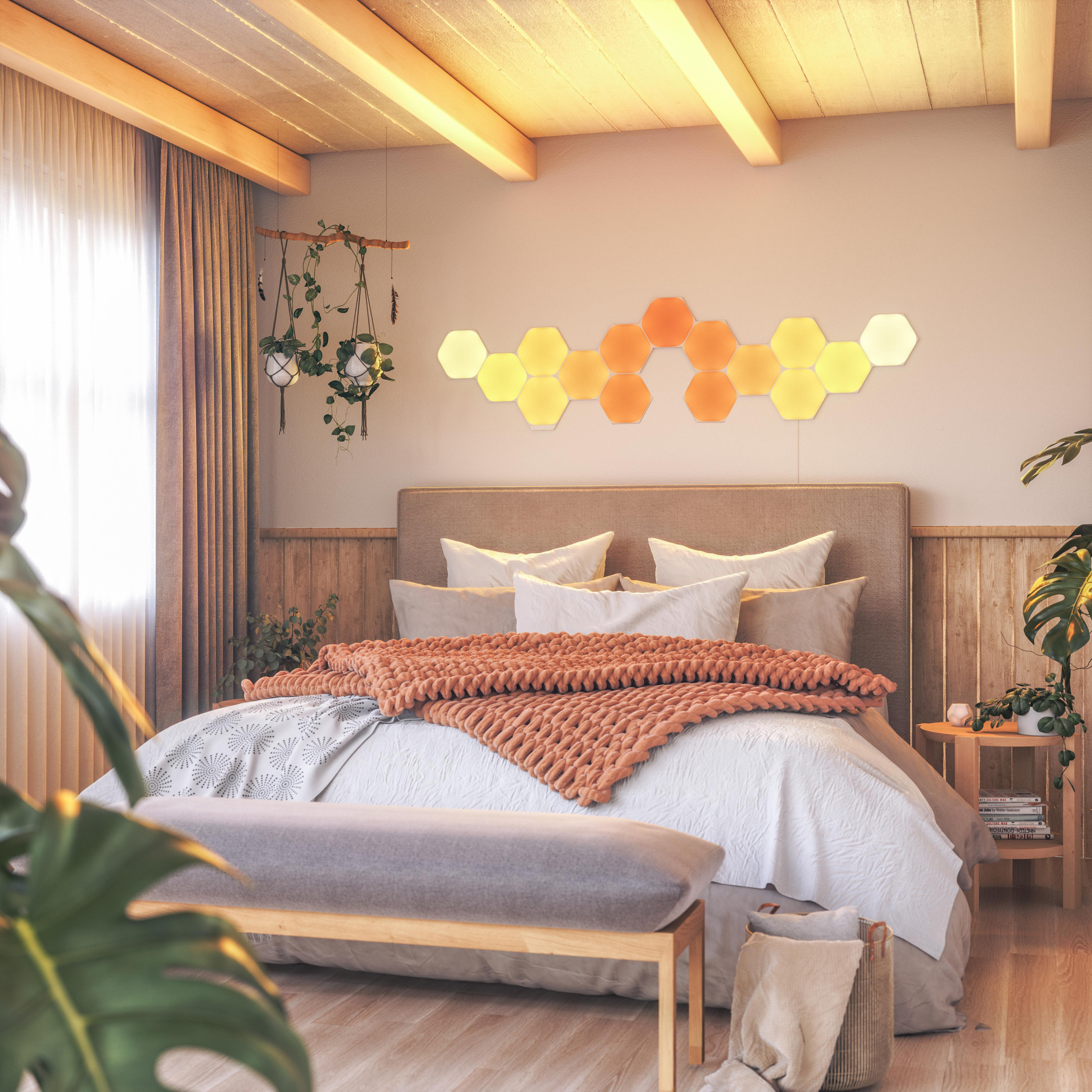 Schlafzimmer mit Bett, Bank, Sechsecklichtern, Holzdecke und Pflanzen.