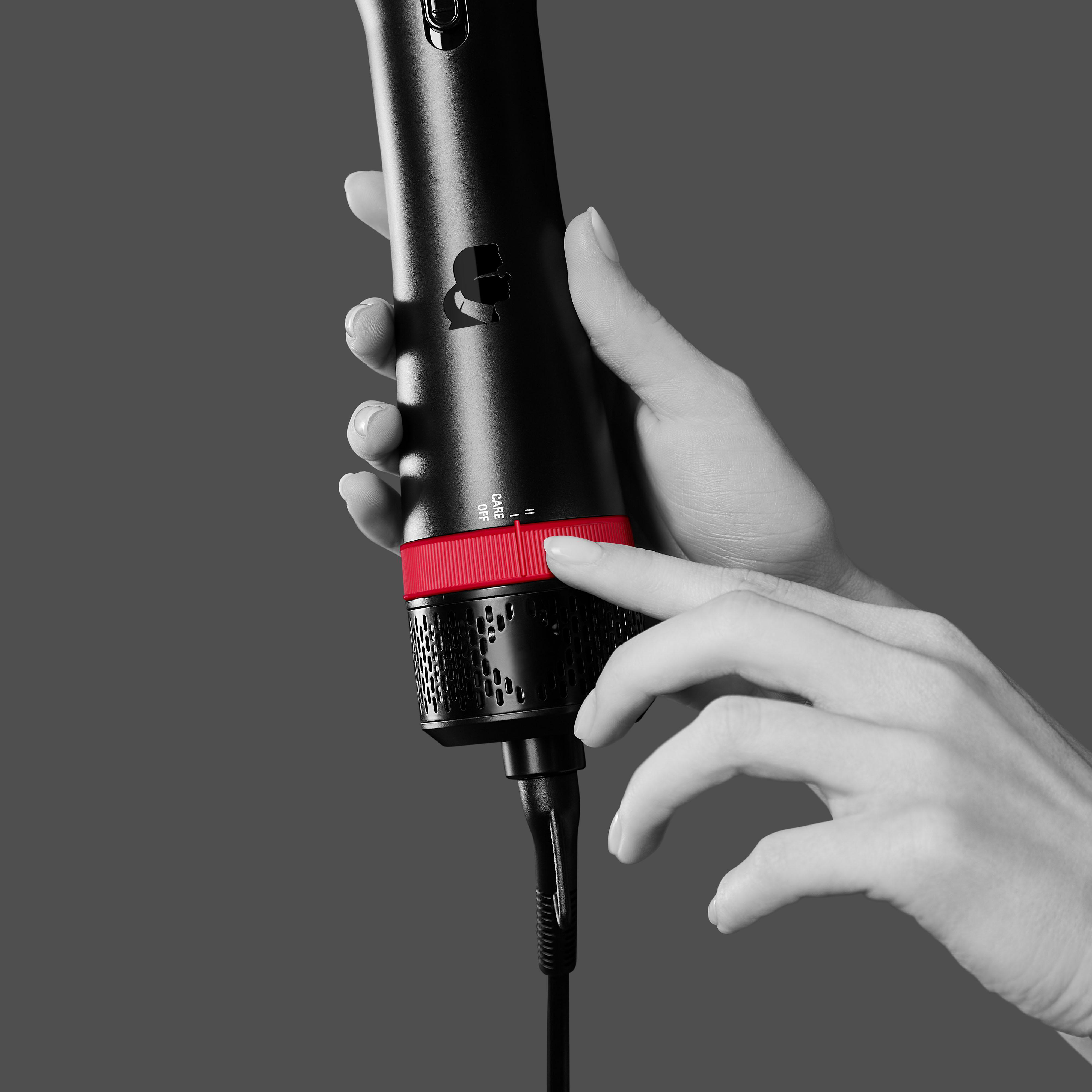 Hände halten ein schwarzes und rotes Haarstyling-Werkzeug.
